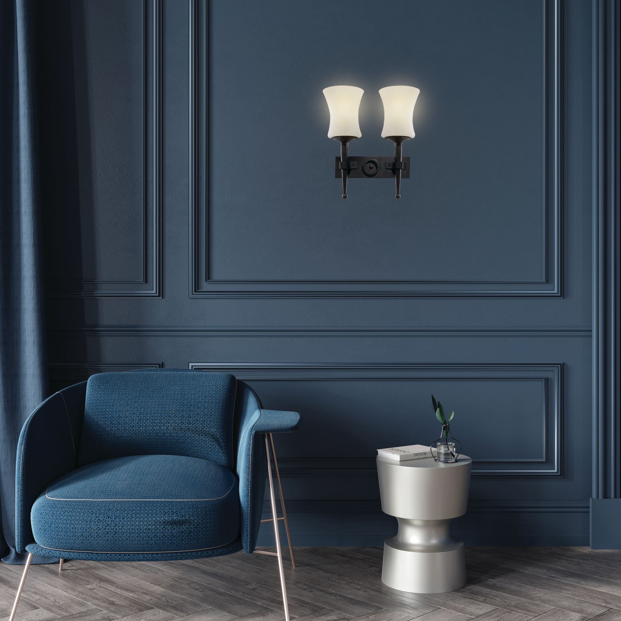 Cartwheel 2 light wall light lit and mounted on a dark blue panelled wall beside a blue armchair and side table