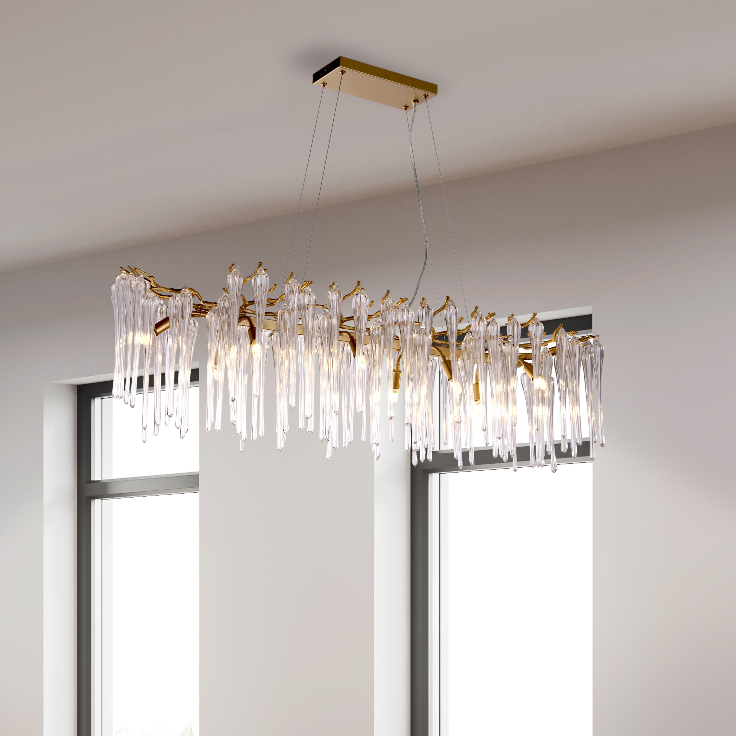 Heritage 10 light pendant in gold suspended from a high ceiling between two tall windows in a bright room