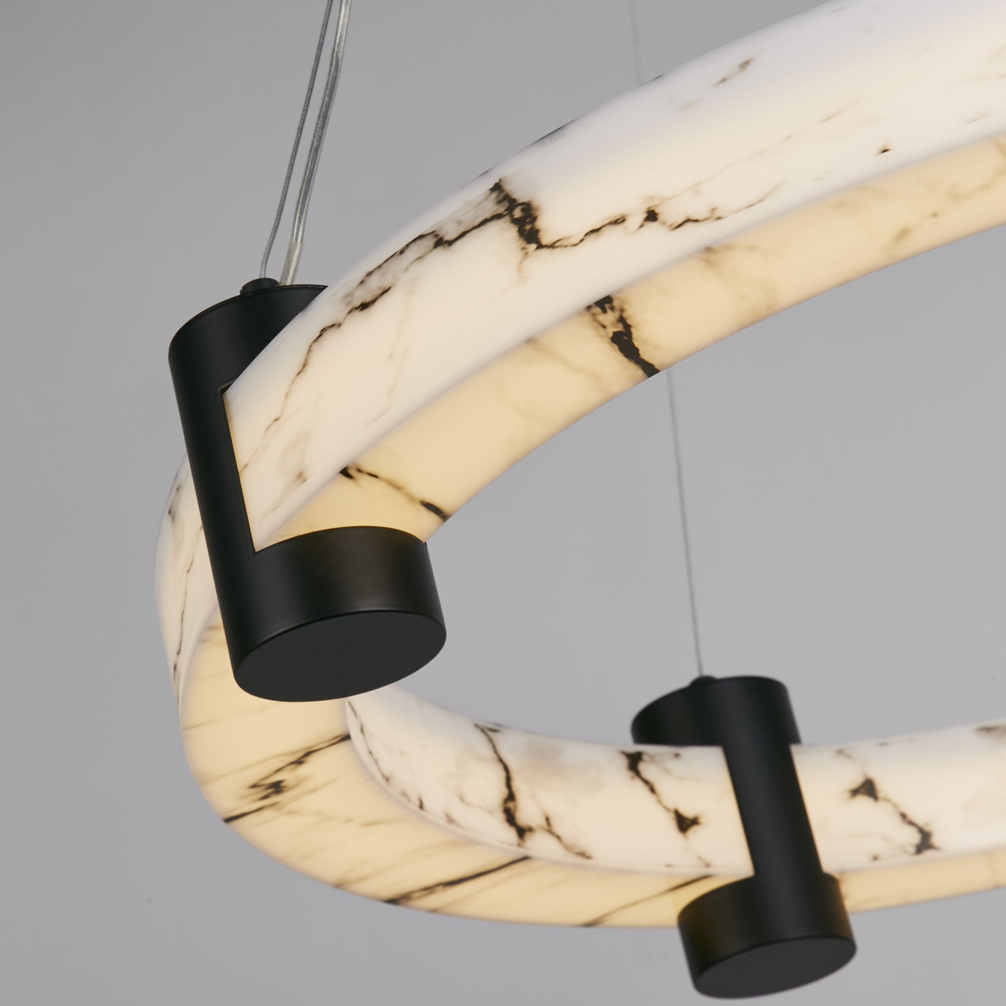 Close up of the Searchlight Moonbeam LED Pendant showing the black metal bracket and the veined marble effect resin ring lit from within