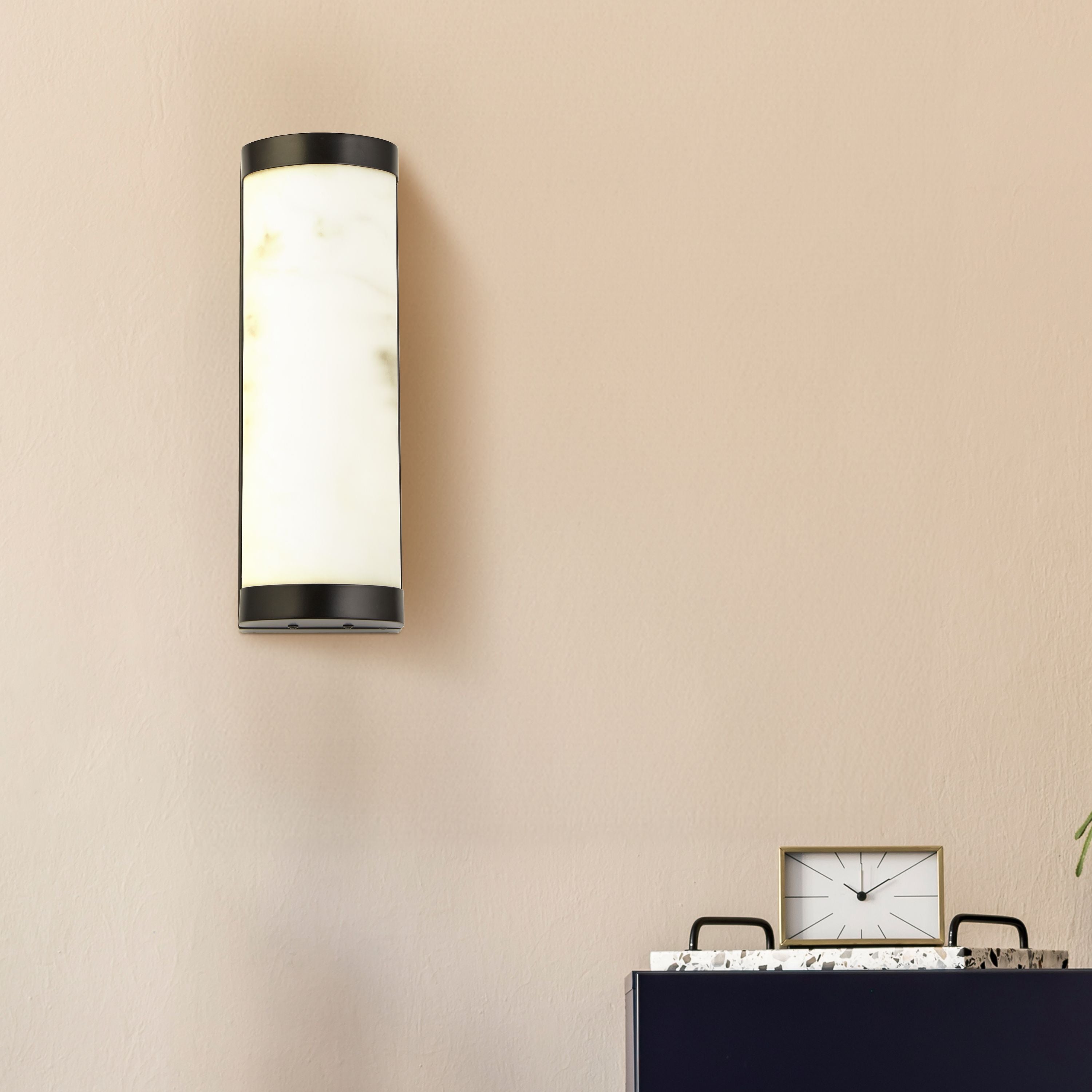 Searchlight Nile LED Wall Light 36cm in matt black styled on a beige wall above a dark console table with a small clock