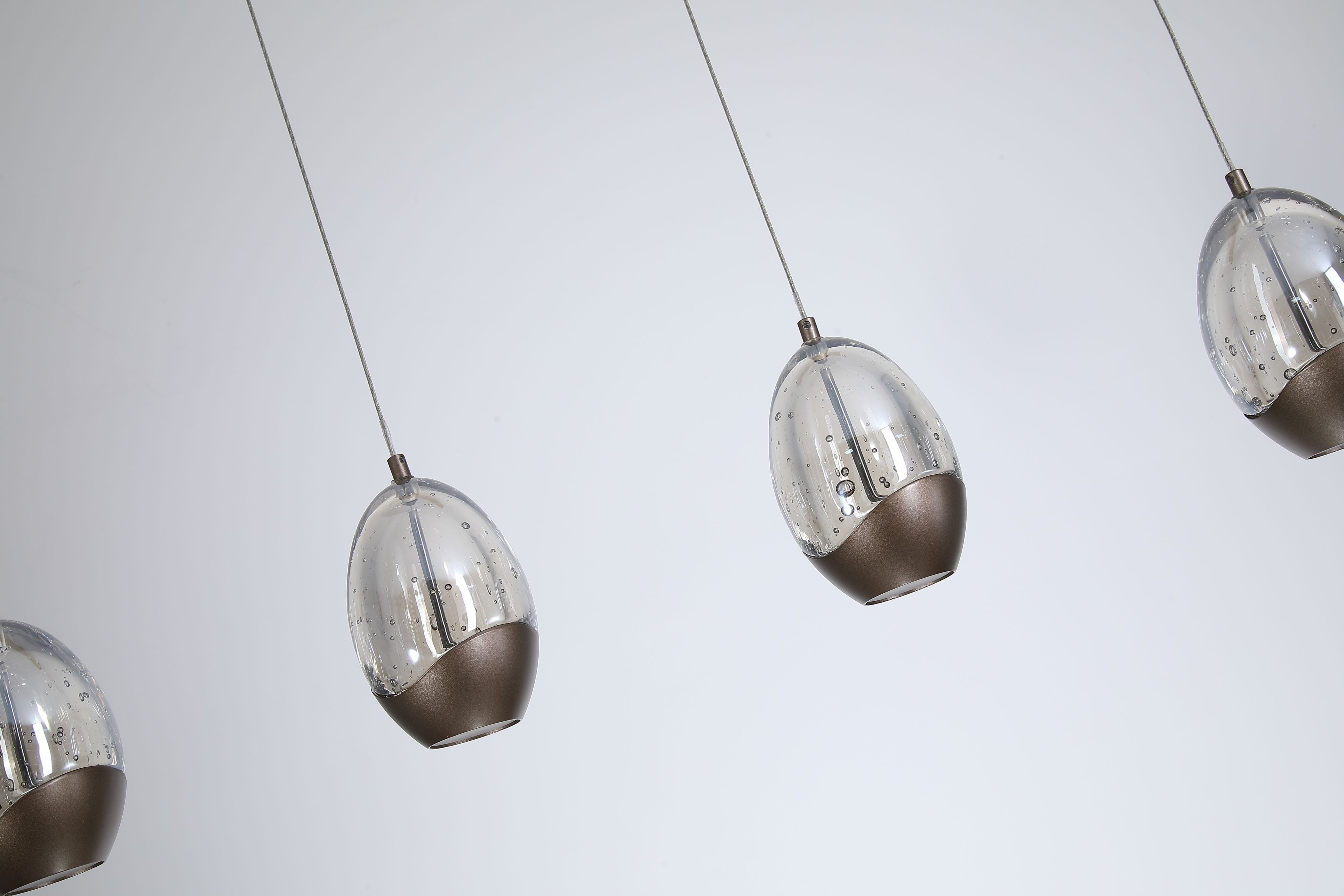 Close up of two Seeds pendant teardrop shades, showing the bubble textured clear glass and dark bronze metal caps