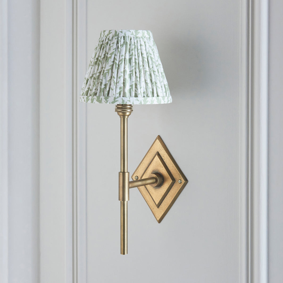 Endon Diamond Tall wall light switched off, antique brass stem and diamond backplate with green leaf pleated shade on grey panelling