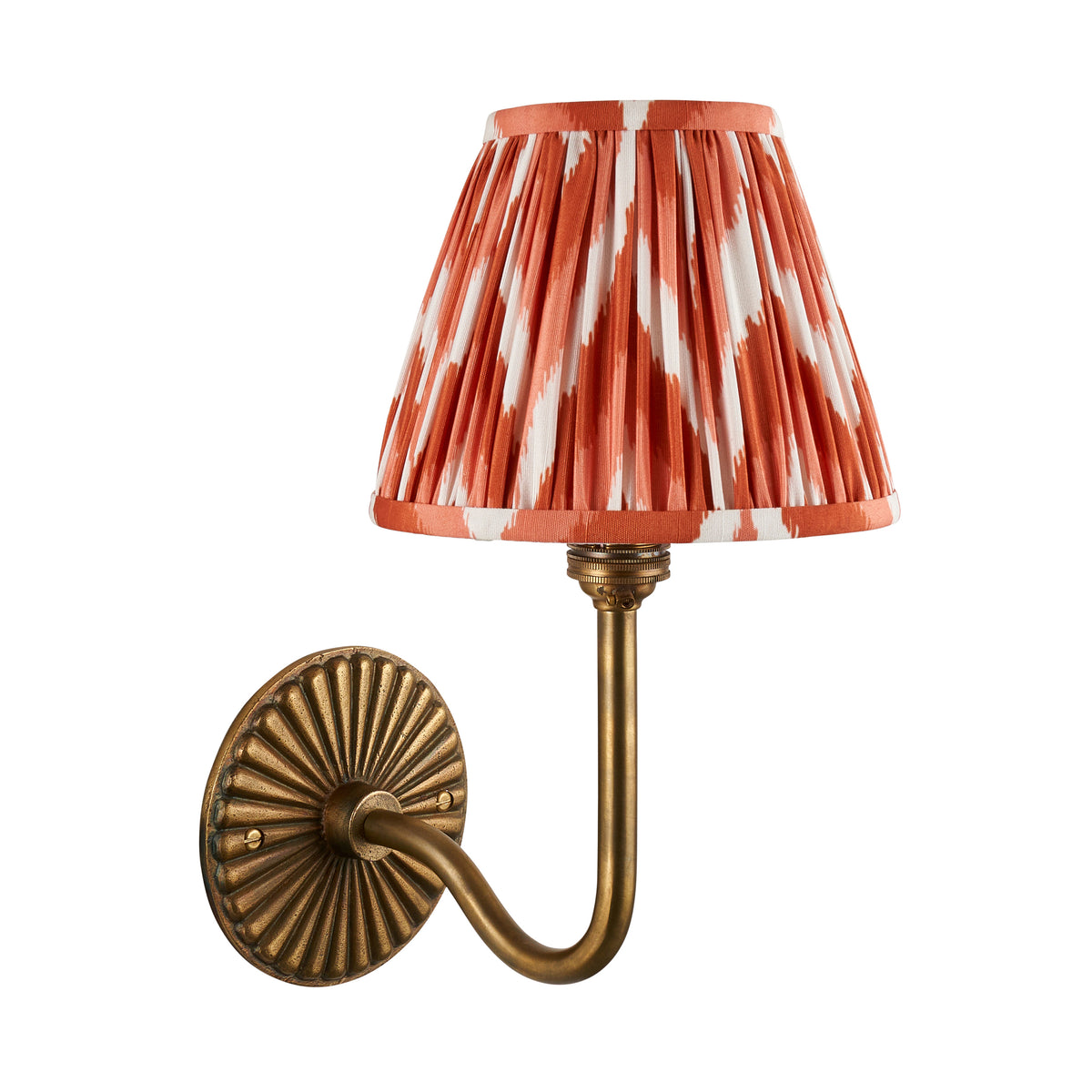 Endon Dahlia Swan antique brass wall light with apricot orange zigzag shade, lit, cut out against a plain white background