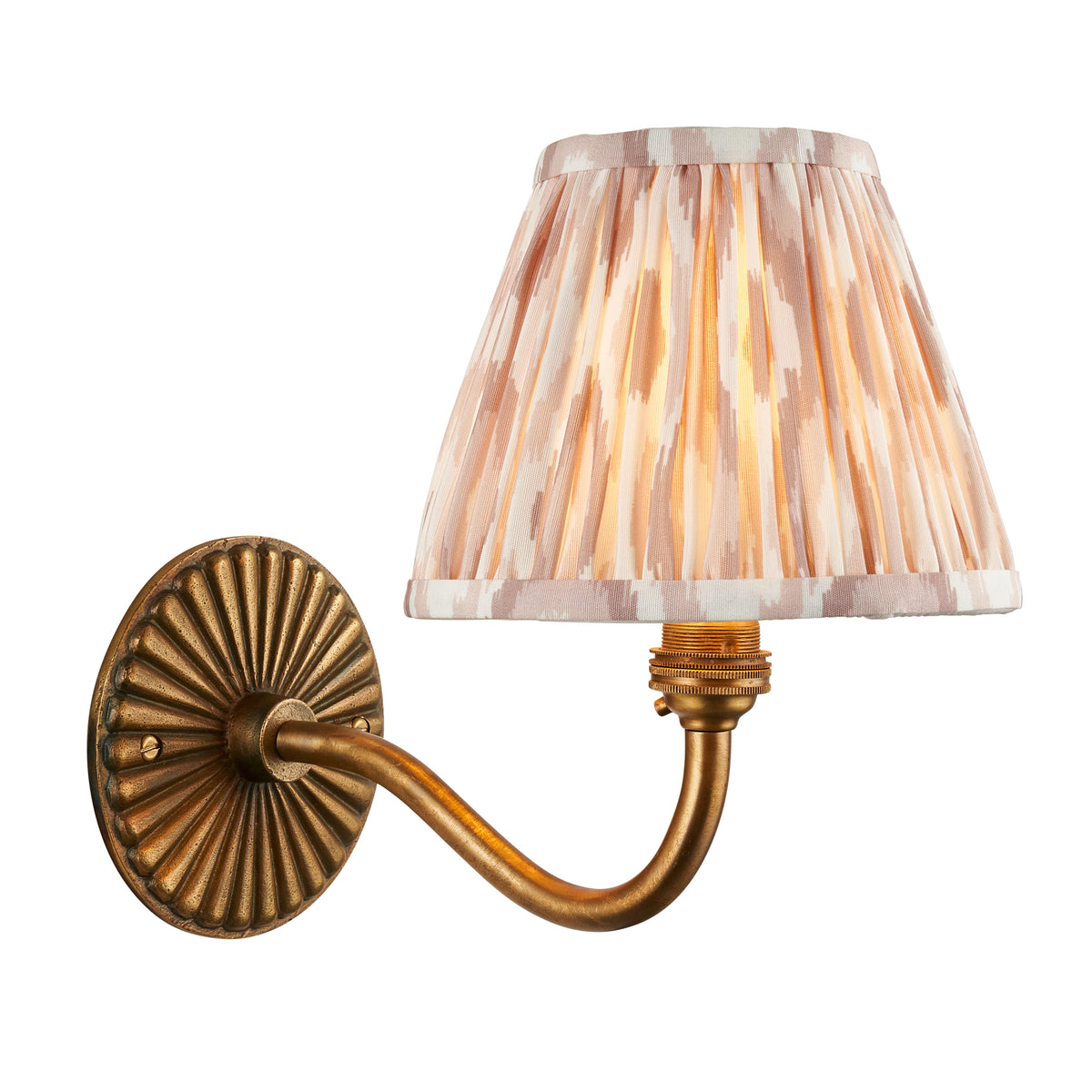 Endon Dahlia Curve wall light in antique brass with neutral pink ikat pleated shade, lit, cut out on white