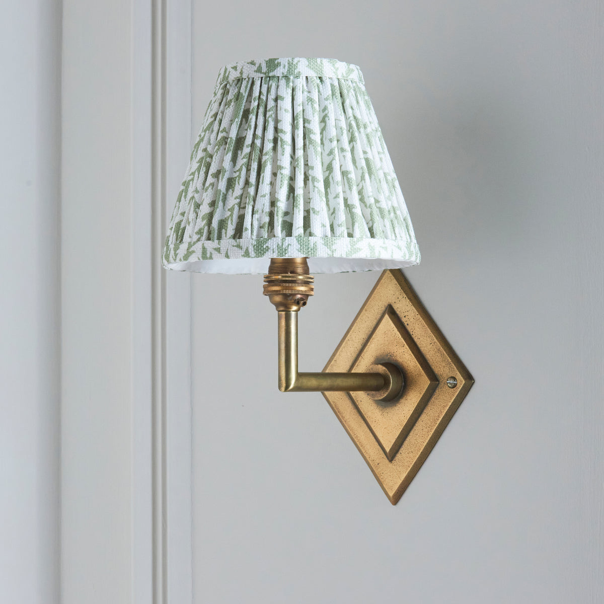 Endon Diamond Angle wall light switched off on a pale grey panelled wall, showing the green and white leaf print shade