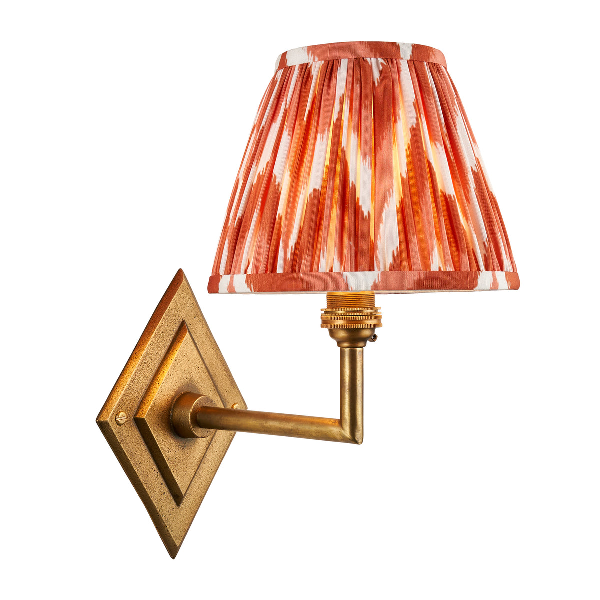 Endon Diamond Angle wall light lit and cut out on white, antique brass diamond backplate with an apricot orange zigzag pleated shade