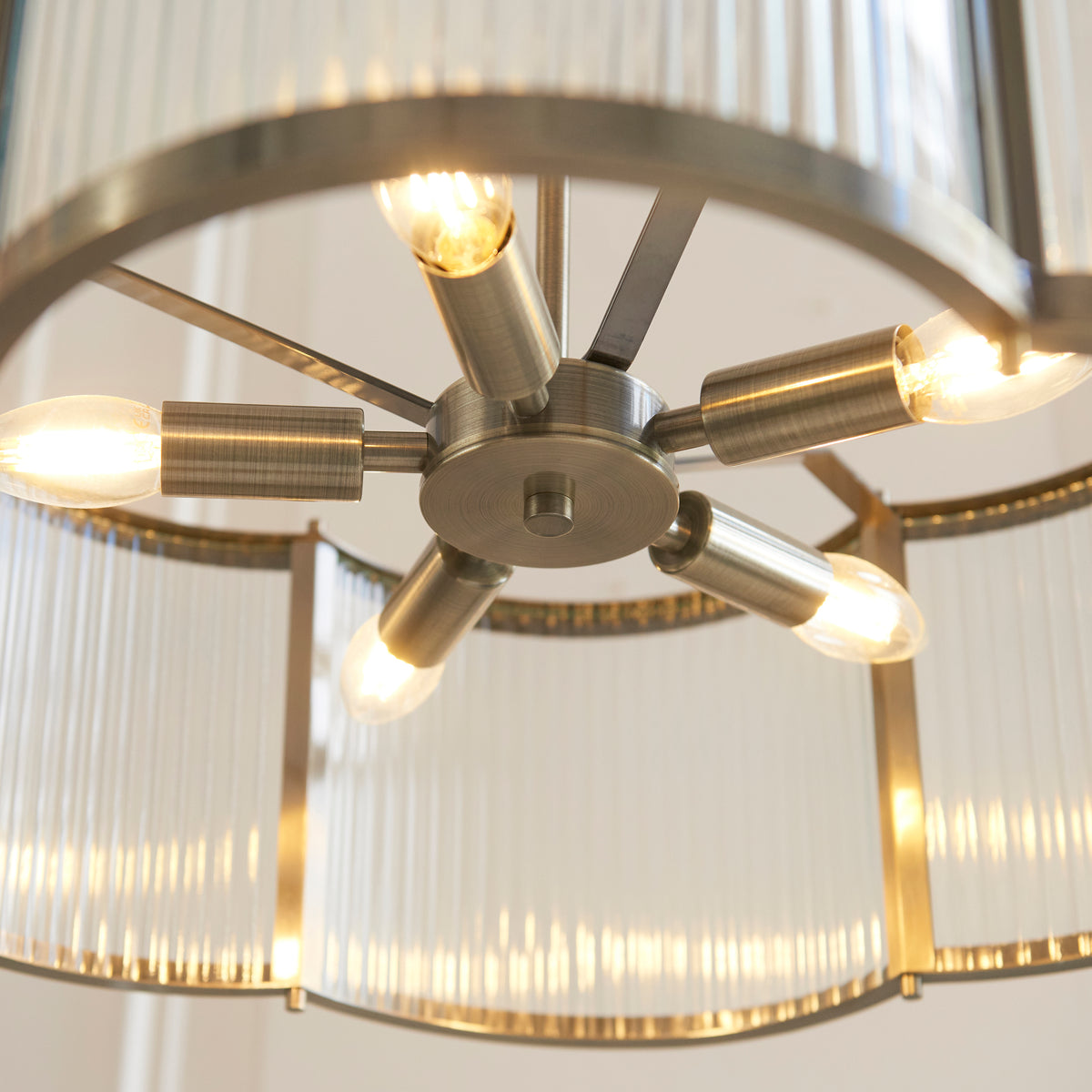 Close up looking up into the Ridgeton Scallop five light pendant showing the brass spoke fitting and bulbs inside the ribbed glass drum shade.