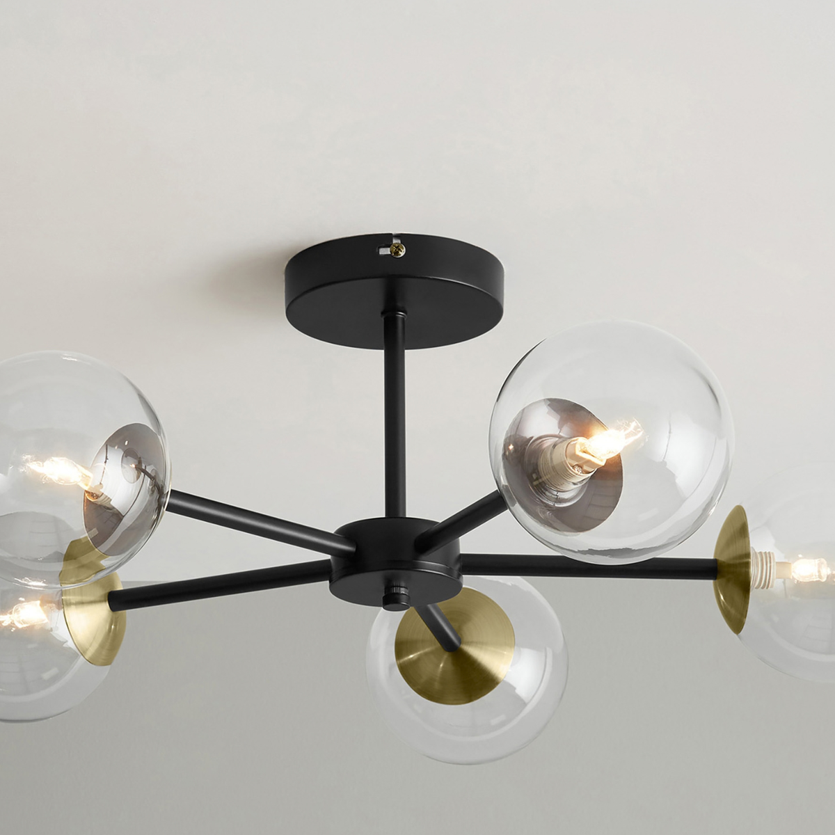 MADE.COM Globe 5 light flush ceiling light close up from below of clear glass globes and brass discs