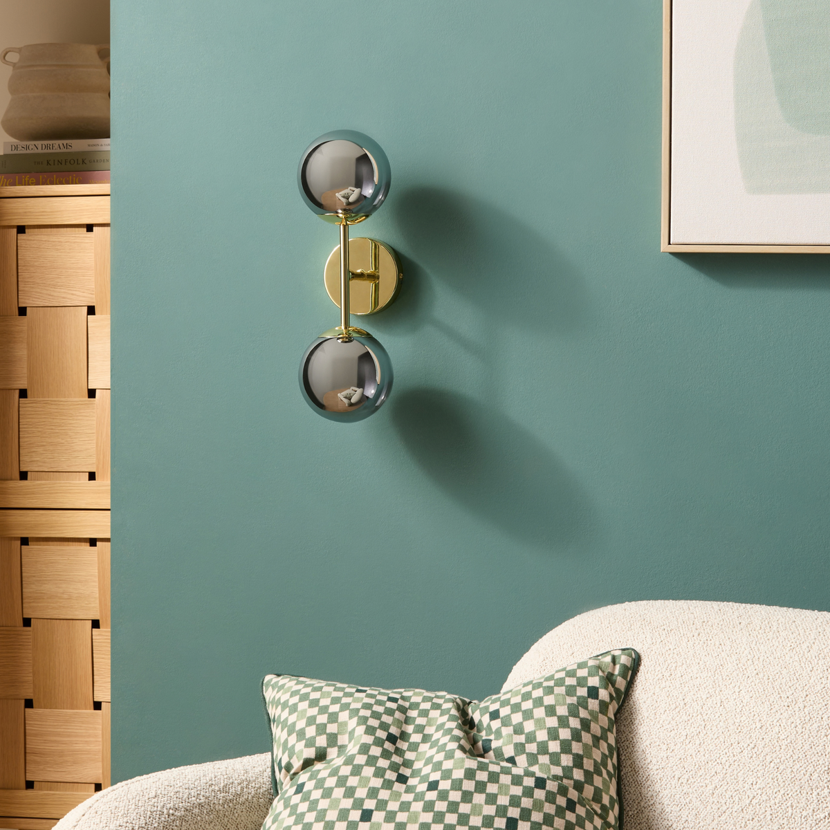 MADE.COM Globe wall light in polished brass with two glass globes, wider room shot beside a sofa