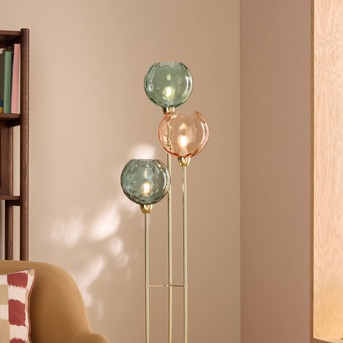 MADE Ilaria floor lamp with dimpled teal and peach glass shades, lit in a room beside a bookcase