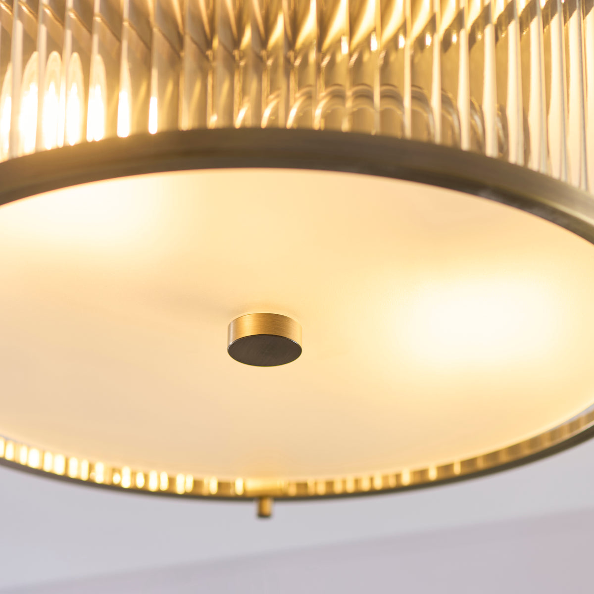 Close up of the frosted glass diffuser and antique brass centre fixing on the underside of the Endon Ridgeton IP44 flush ceiling light