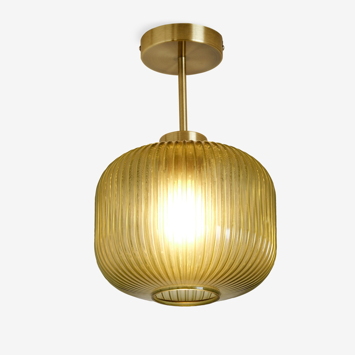 MADE Briz flush ceiling light in antique brass with ribbed glass shade, studio shot glowing warm yellow