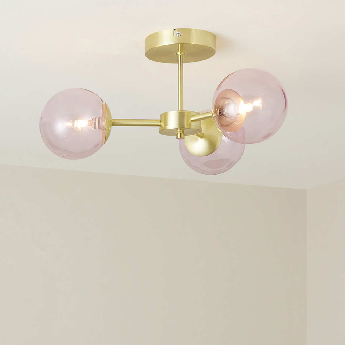 MADE.COM Globe 3 light flush ceiling light in brushed brass with pink tinted glass shades, lifestyle shot
