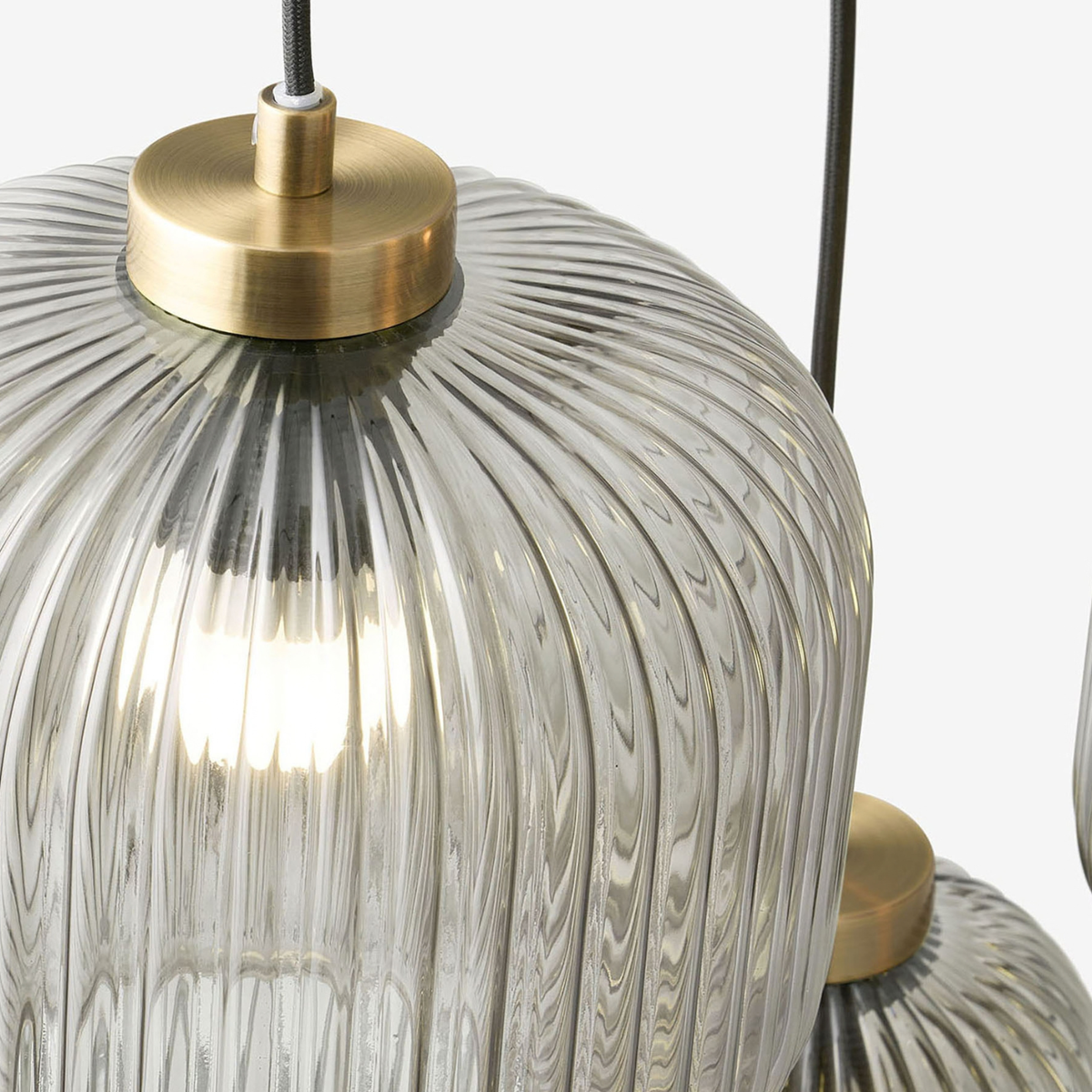 Close up of ribbed grey glass shade and antique brass cap on MADE.COM Briz cluster pendant