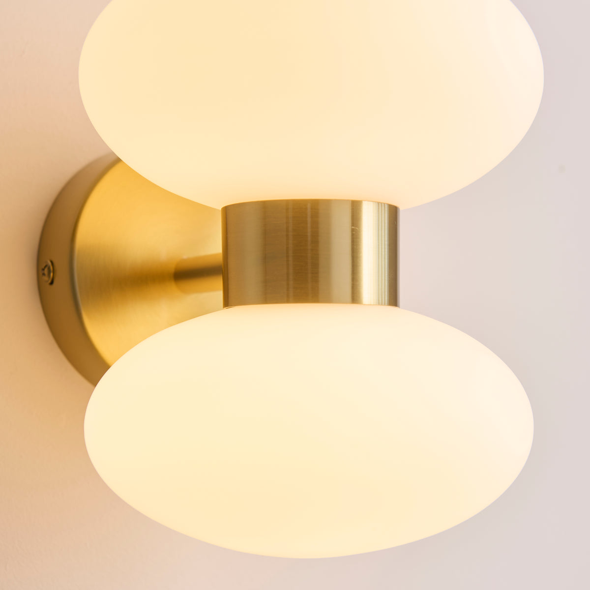 Plain product shot on a white background of the Endon Rossano 2 light wall light in warm brass with opal glass shades, lit, angled view