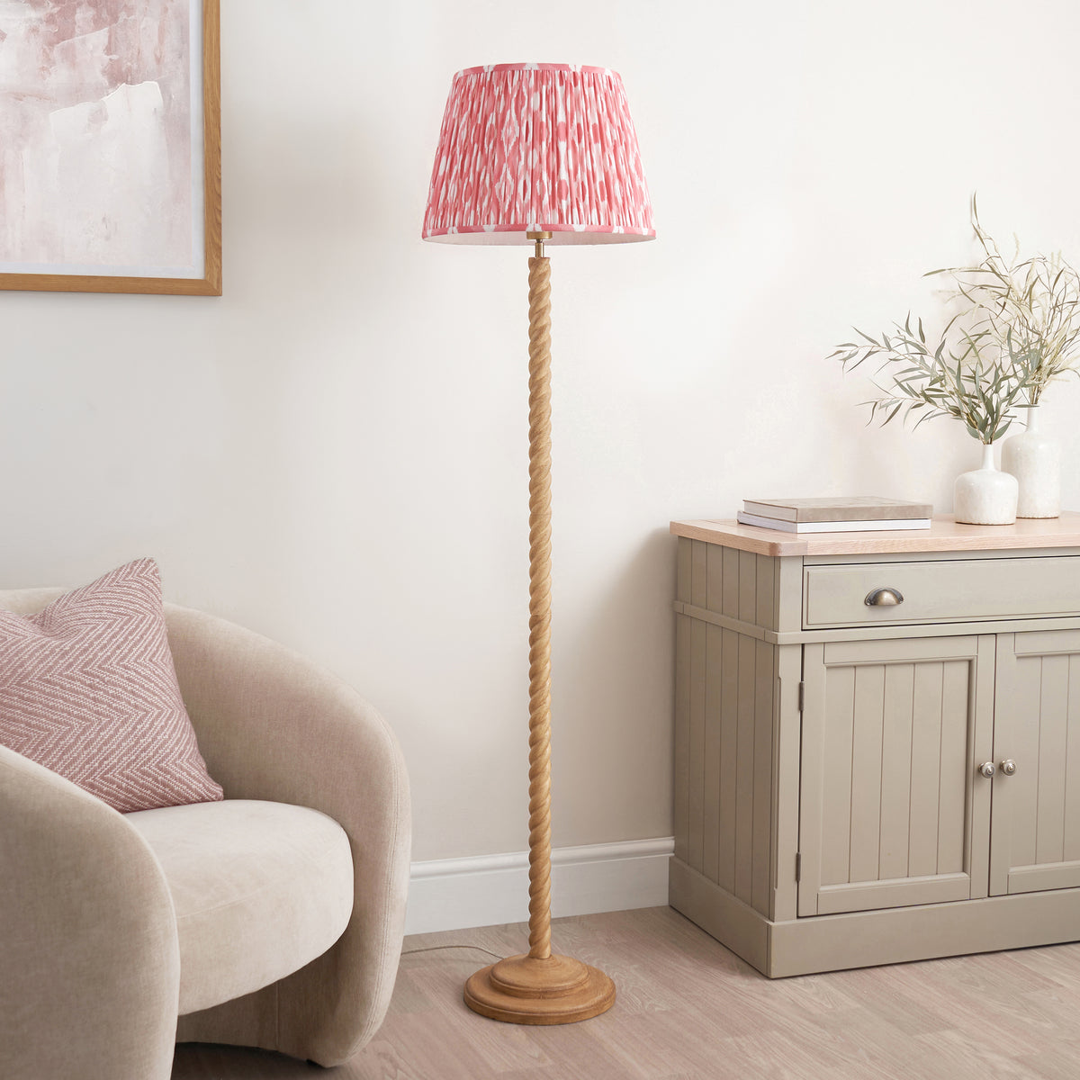 Endon Twist floor lamp unlit in a living room, oak effect twisted stem and pink ikat shade beside a boucle armchair and sideboard