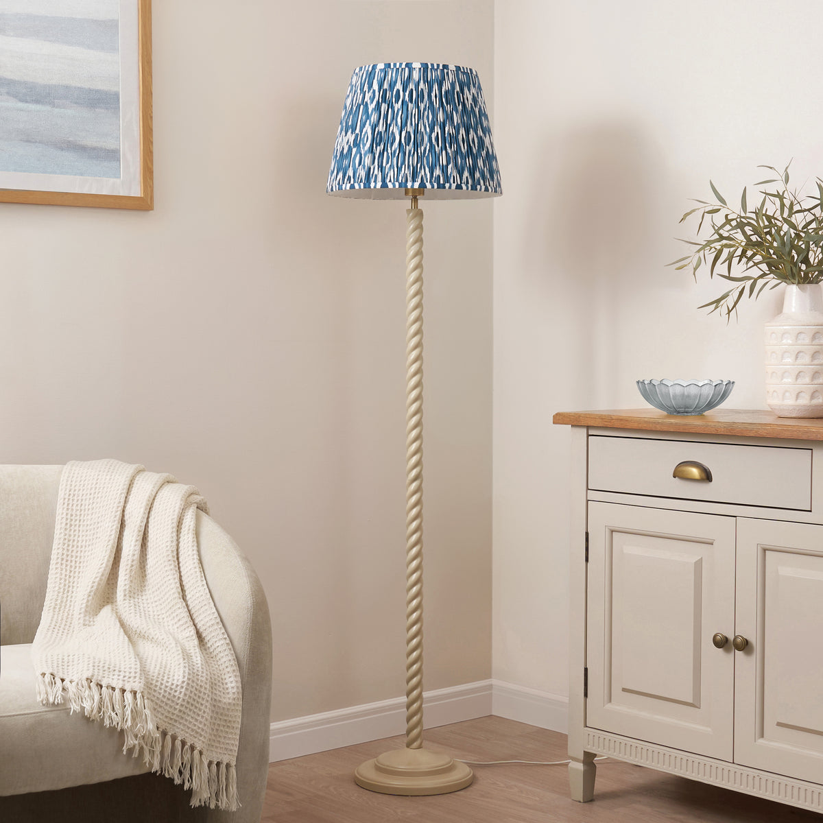 Endon Twist floor lamp with marlin blue ikat shade unlit in a living room corner between an armchair and a painted sideboard
