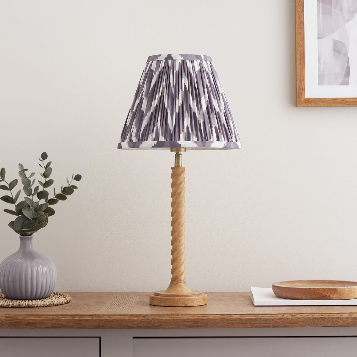 Endon Twist table lamp unlit, oak effect twisted stem and pearl grey zigzag shade on an oak sideboard with a vase and wooden bowl