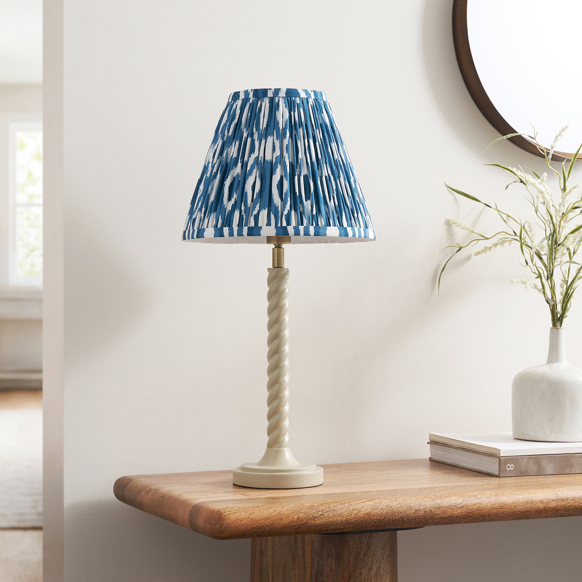 Endon Twist table lamp switched off on a wooden console table, showing the crisp blue and white ikat print and almond white twist base