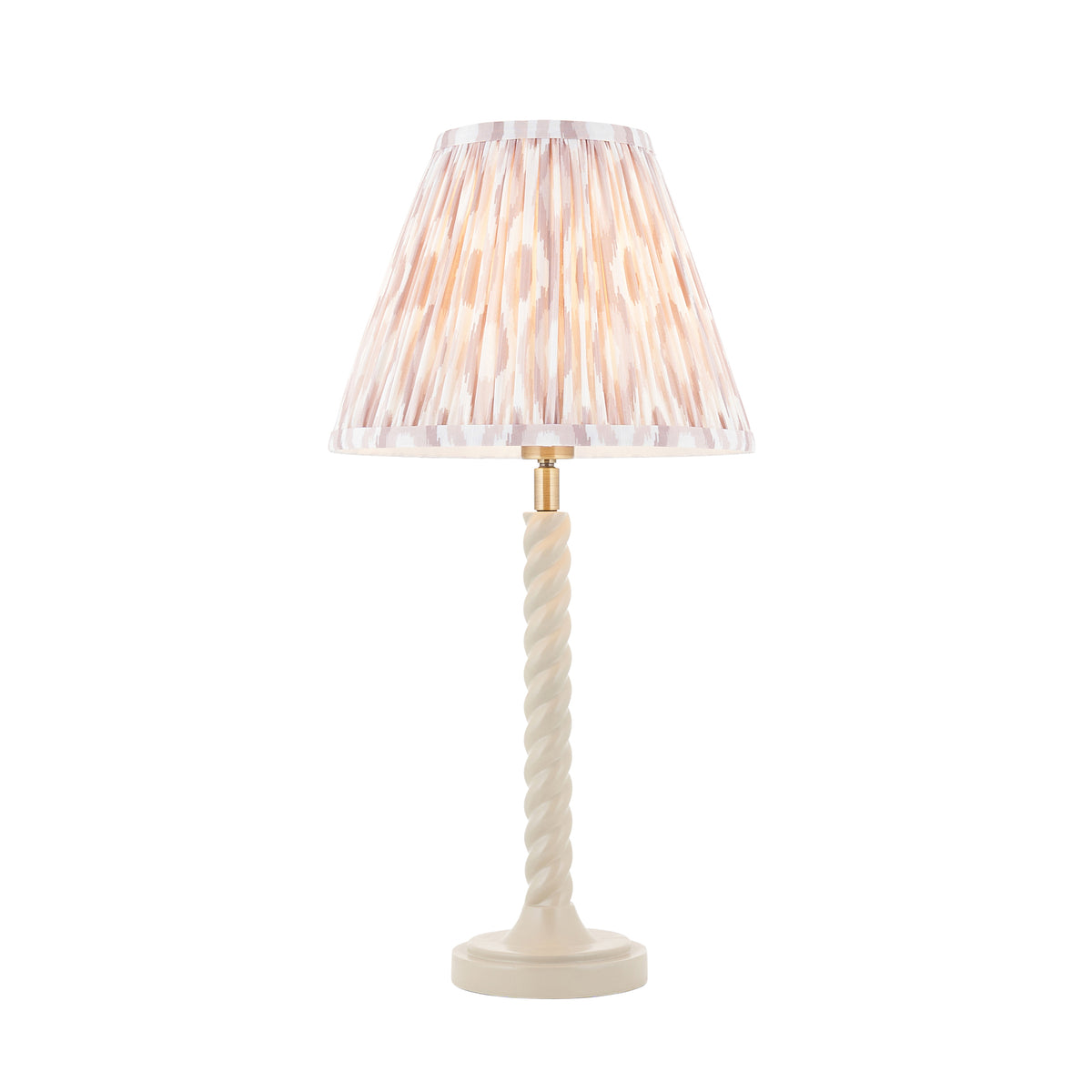Endon Twist table lamp lit, cut out on white, satin almond white twisted stem with a pleated neutral blush ikat shade