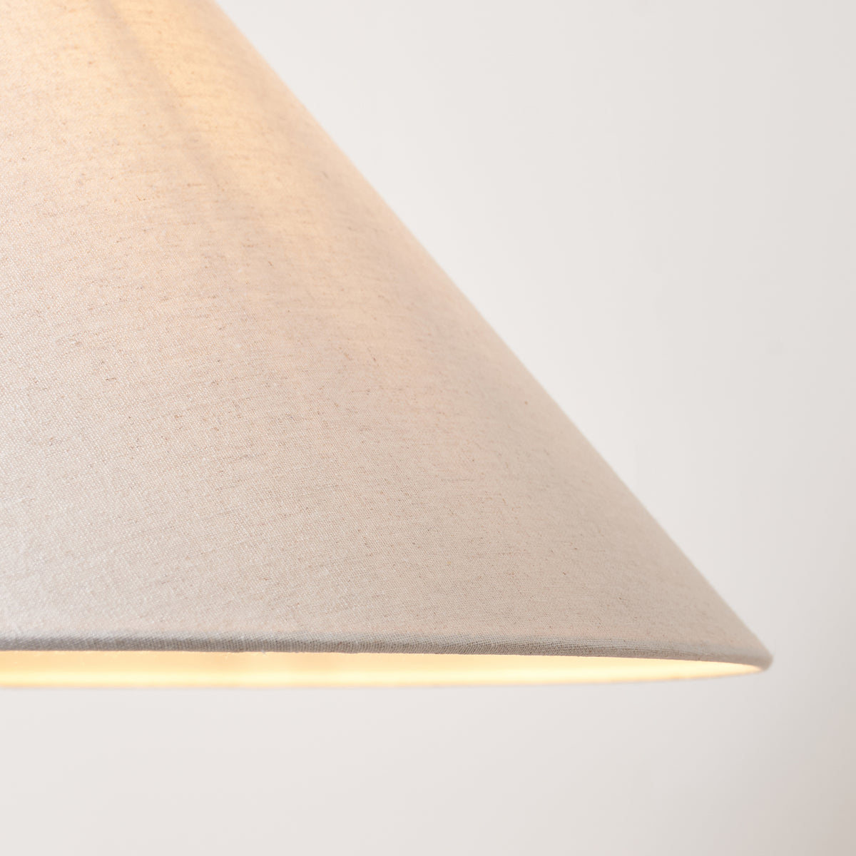 Detail of the natural linen fabric texture on the Endon Avalon coolie shade, lit from inside with a warm glow at the rim