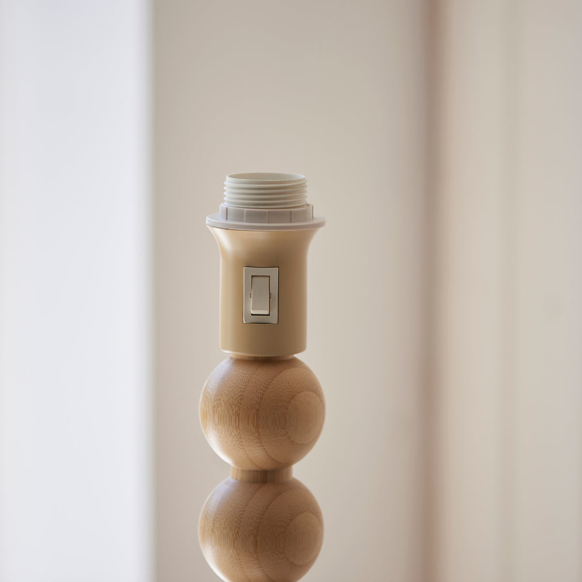 Close up of the Endon Cane floor lamp E27 lamp holder with its on off rocker switch and threaded ring above the natural bamboo spheres, shade removed