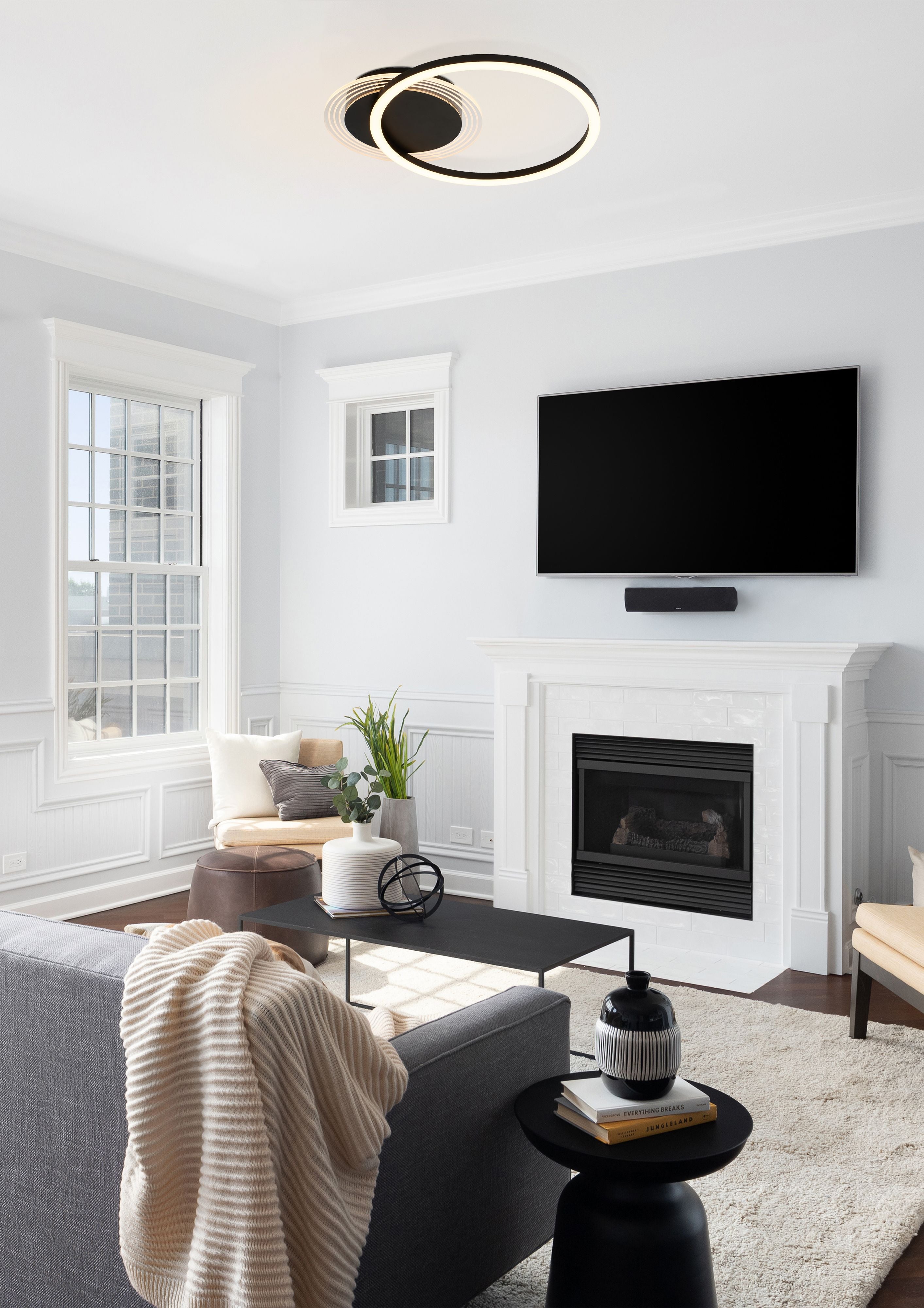 Contour single ring LED flush light in matt black installed above a fireplace in a light filled living room