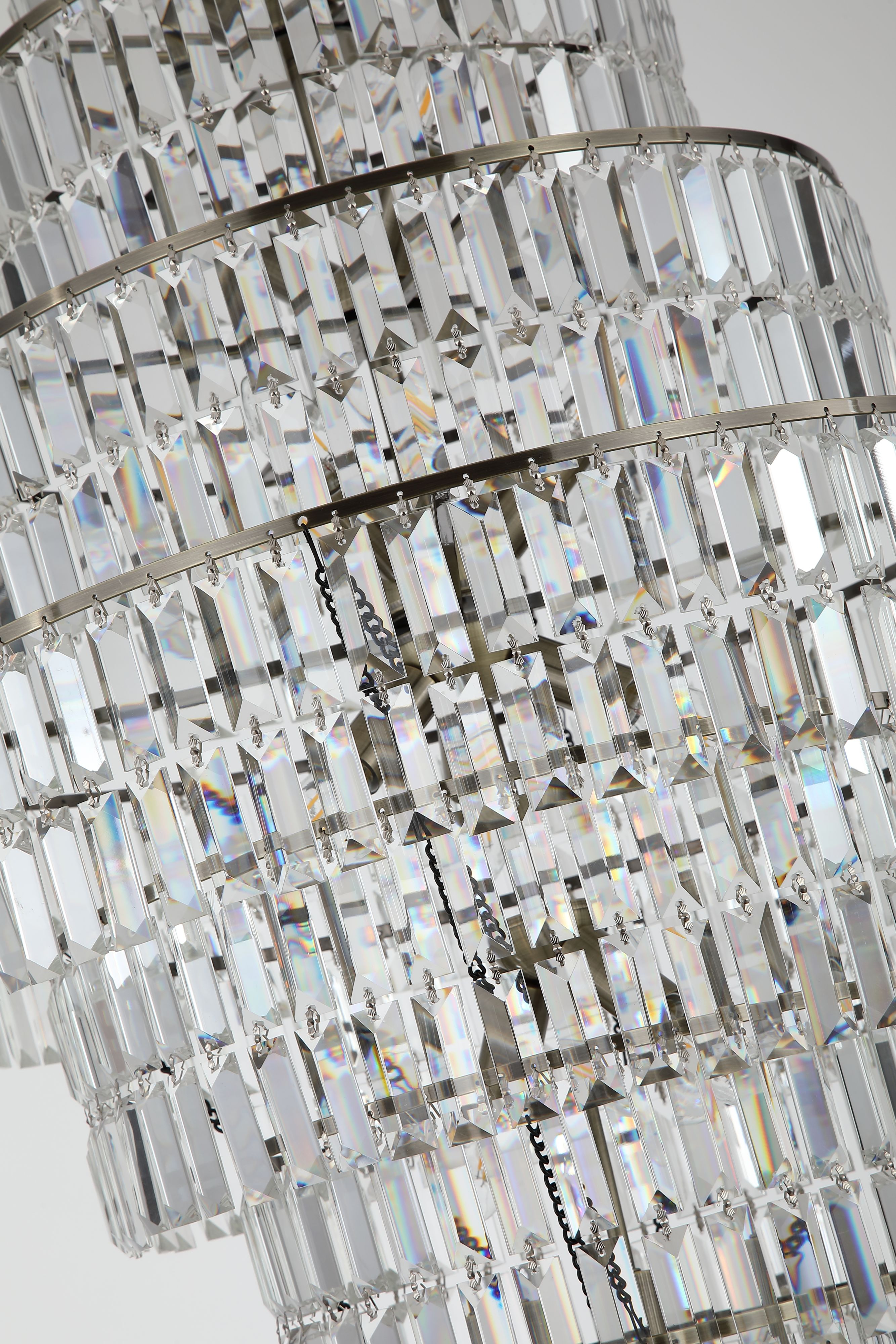 Close up of the Empire chandelier's clear crystal tiers and antique brass frame, showing the faceted glass detail lit from within