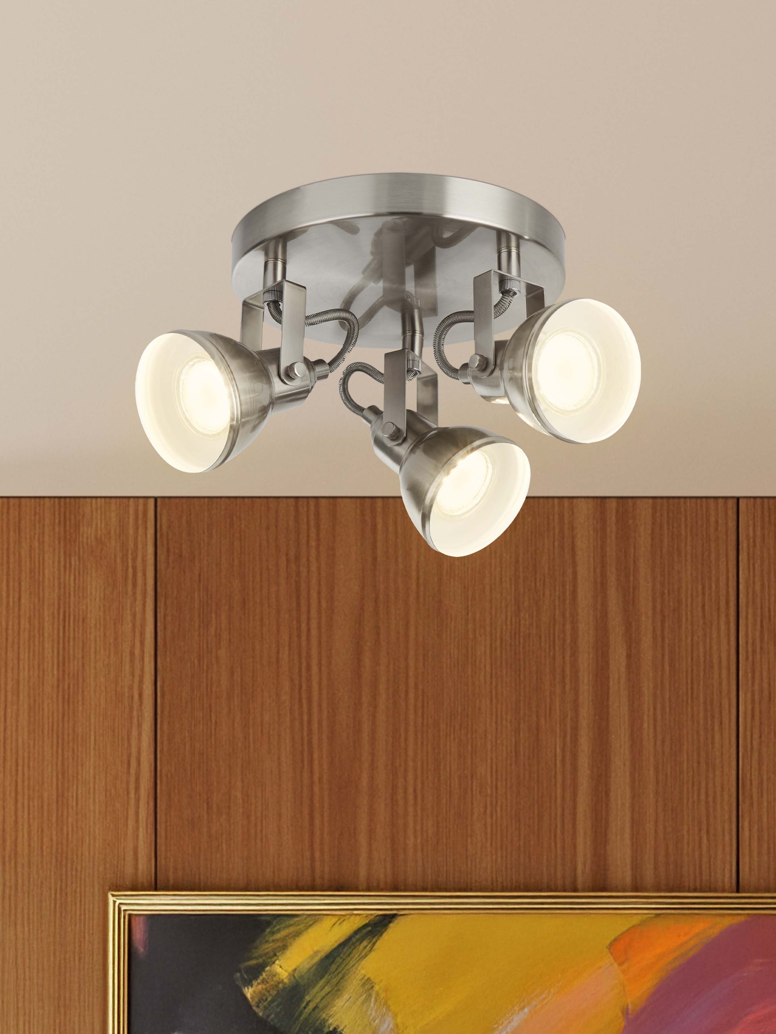 Searchlight Focus 3 light spotlight in satin silver mounted on a ceiling above wood panelling, lit above a framed abstract artwork
