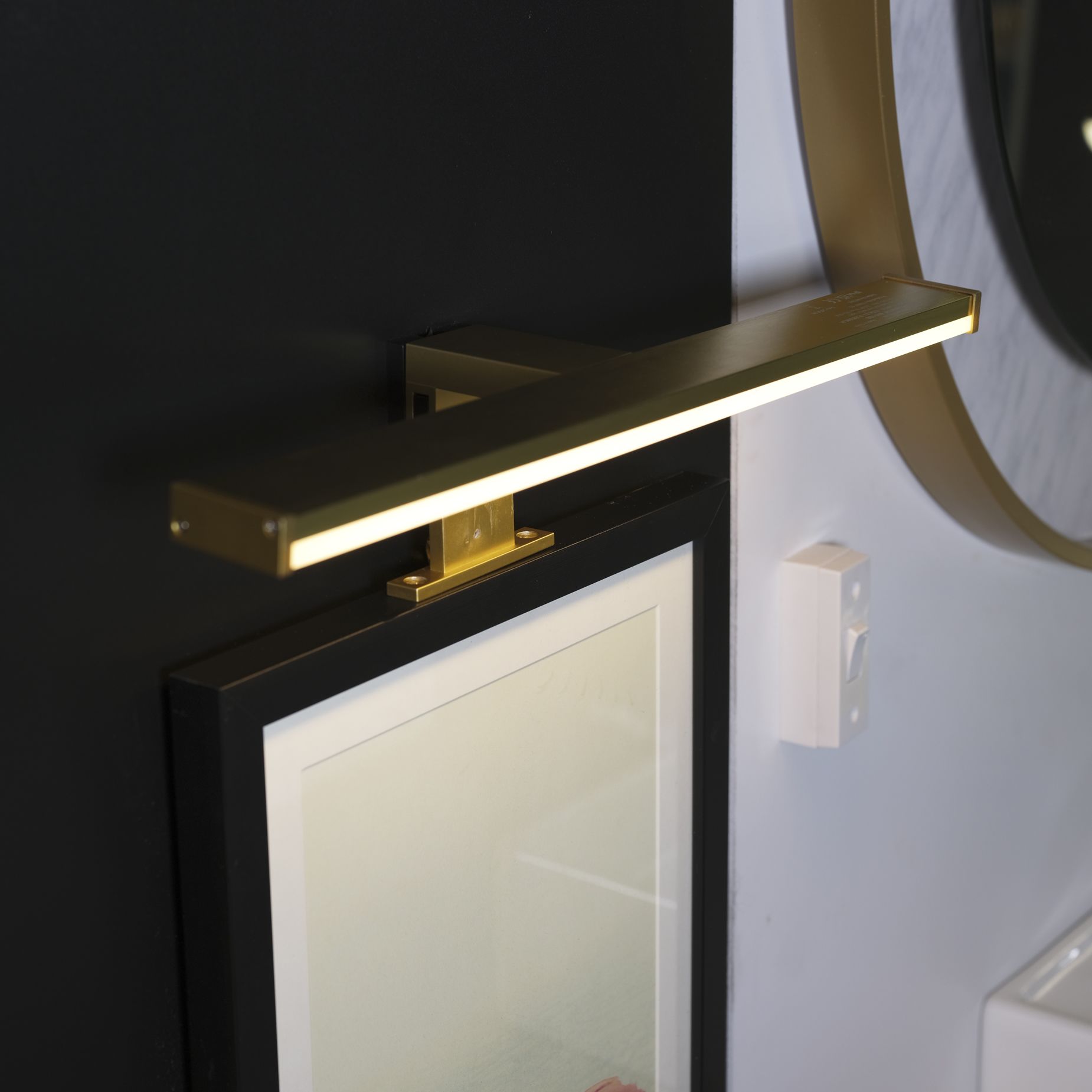Kos matt gold mirror light fixed above a black framed mirror in a styled bathroom