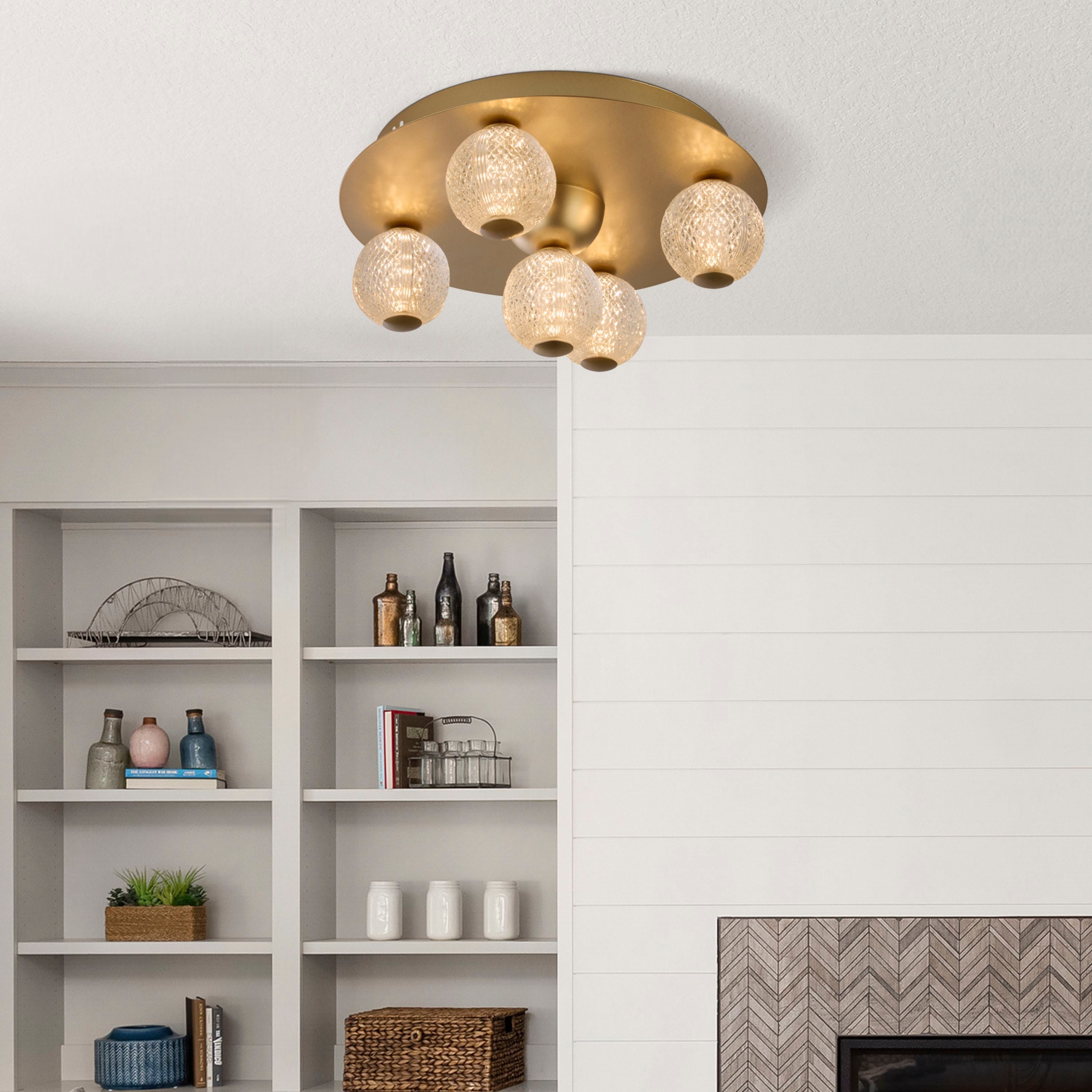 Asteroid LED flush ceiling light in gold installed above a living room shelving unit and fireplace