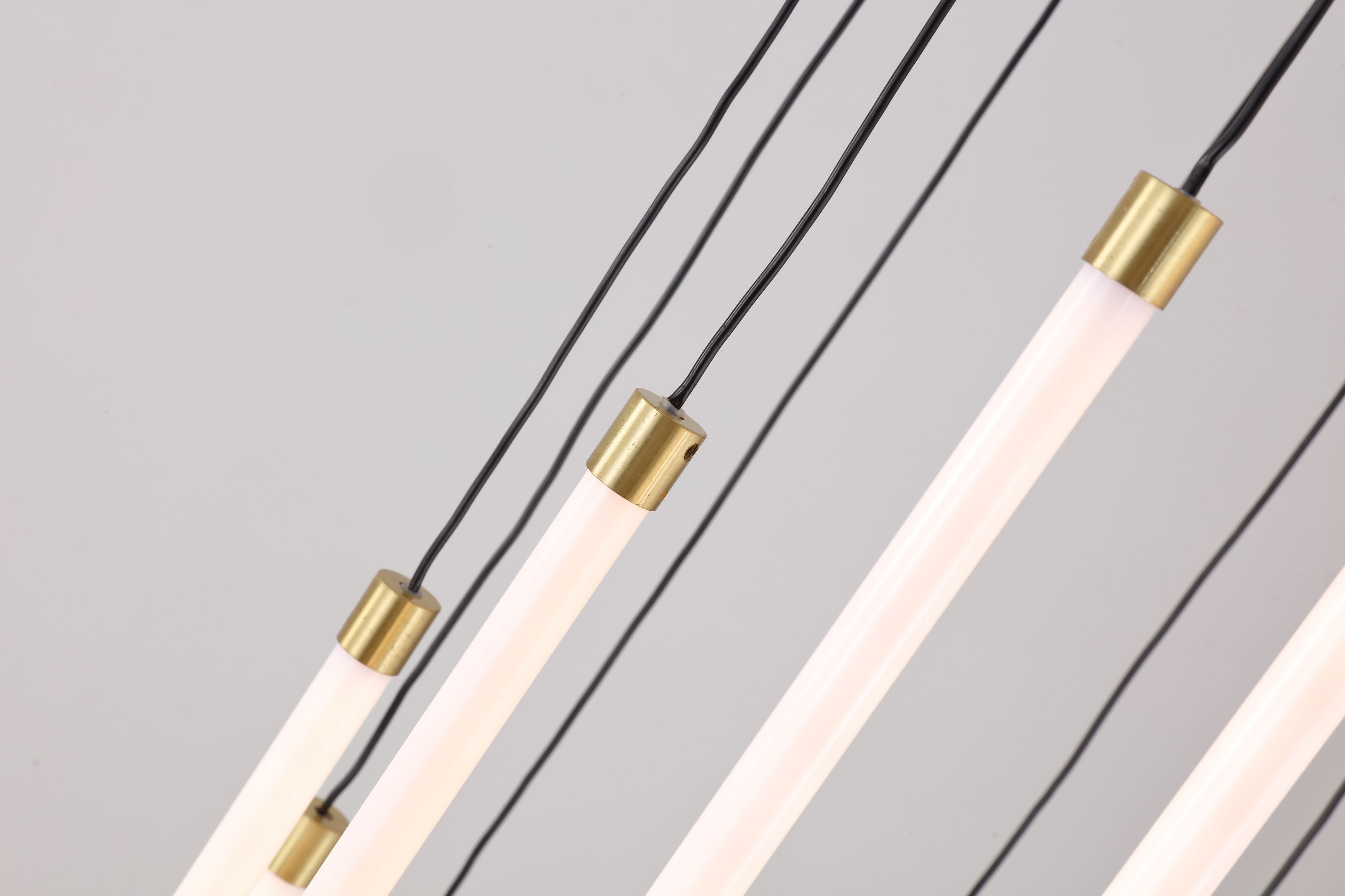 Close up of the Flare pendant's satin brass end caps and illuminated LED tubes