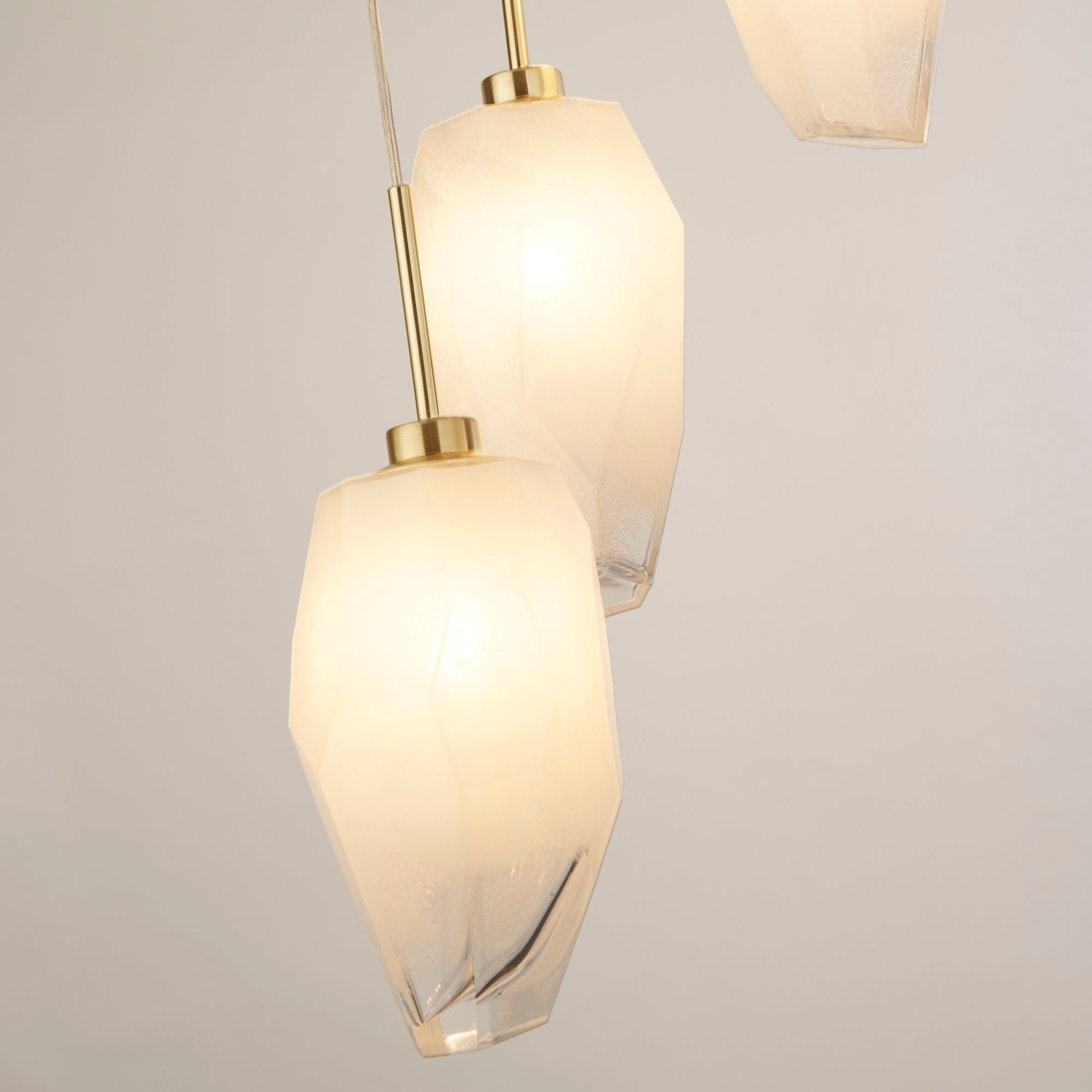 Close up of two Rocky multi drop pendant shades, showing the faceted glass texture lit from within