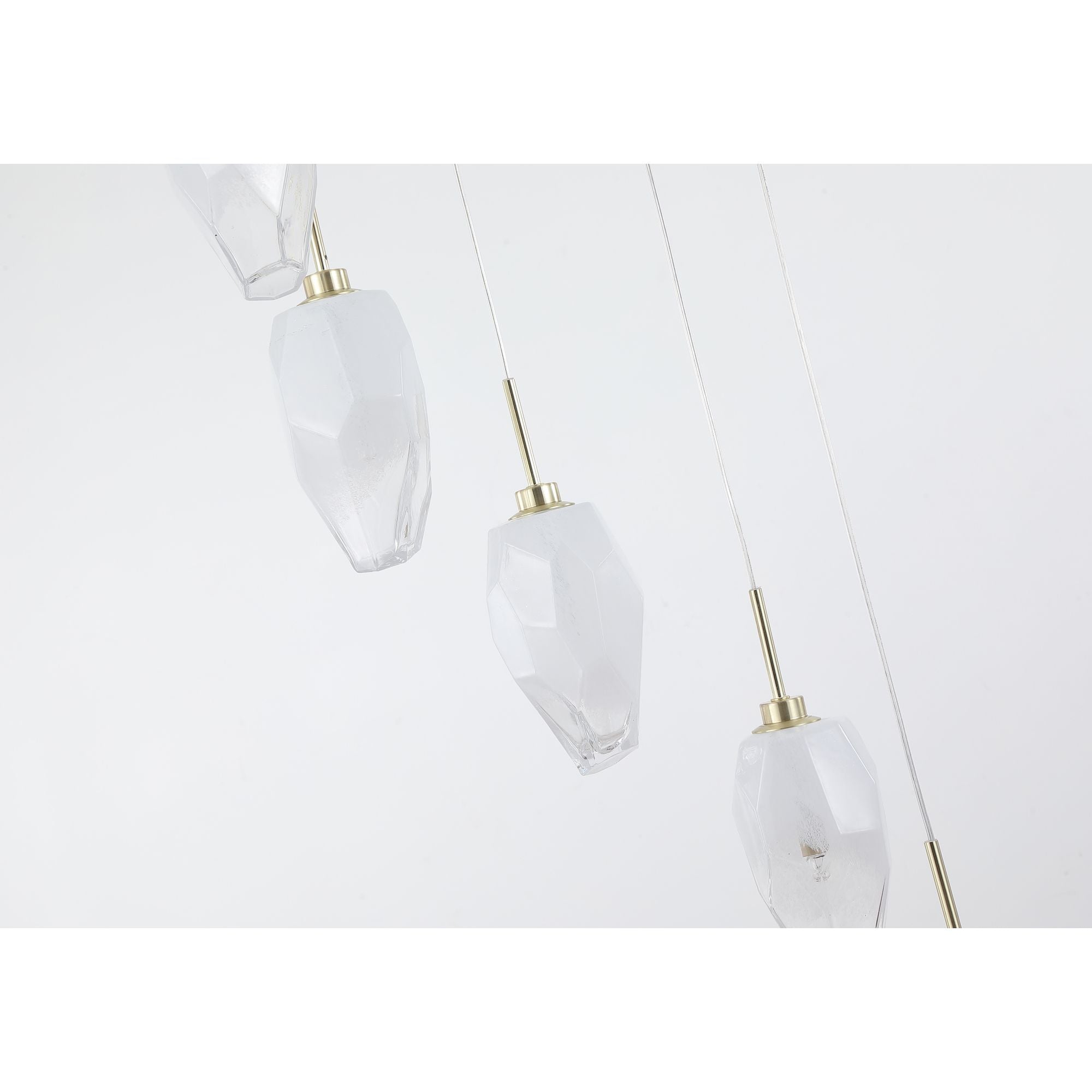 Close up of the Rocky pendant's frosted and clear faceted glass shades on satin brass drop rods, showing the textured glass detail