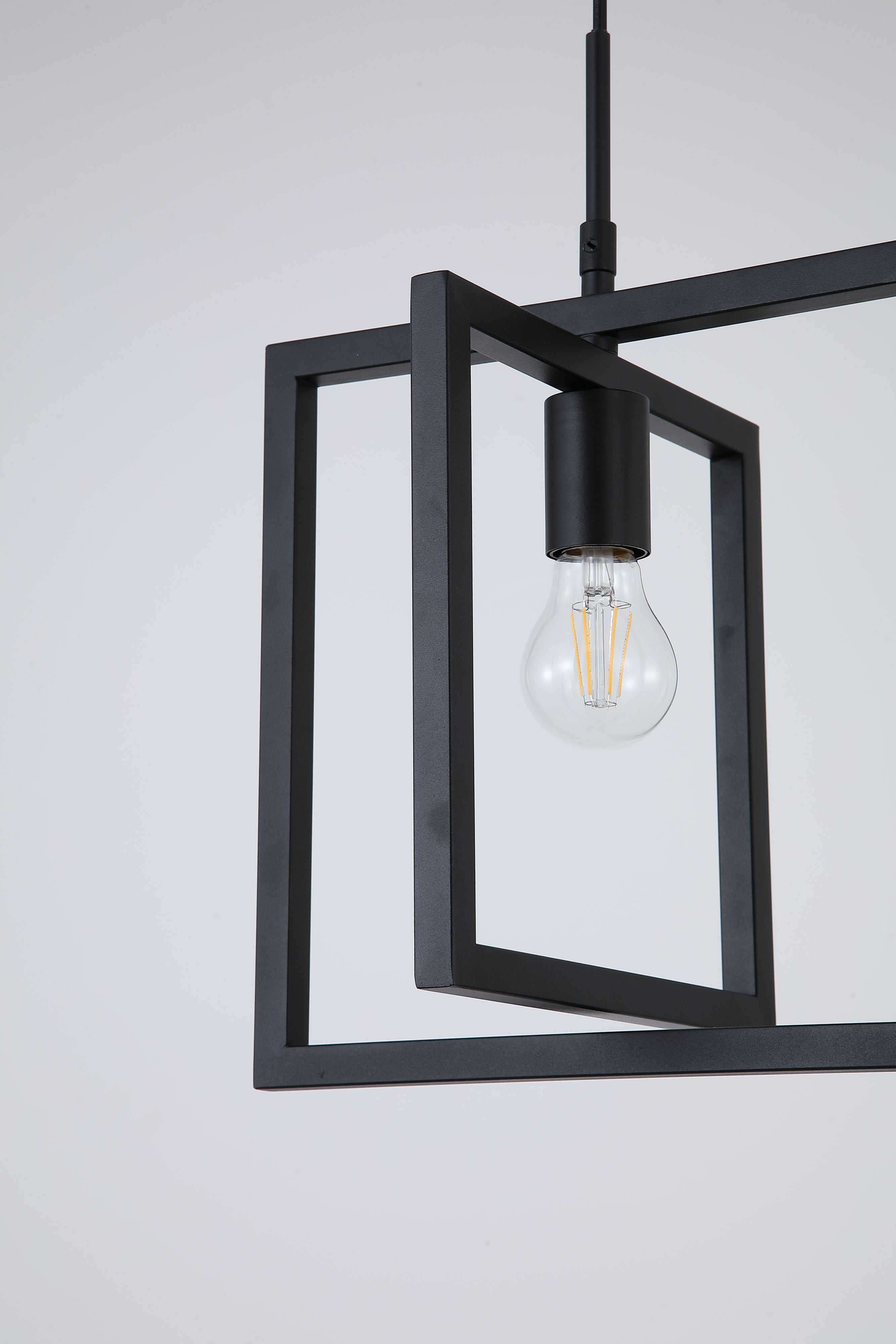 Close up of the Searchlight Plaza pendant where the two black frames cross, showing the lamp holder and exposed filament bulb