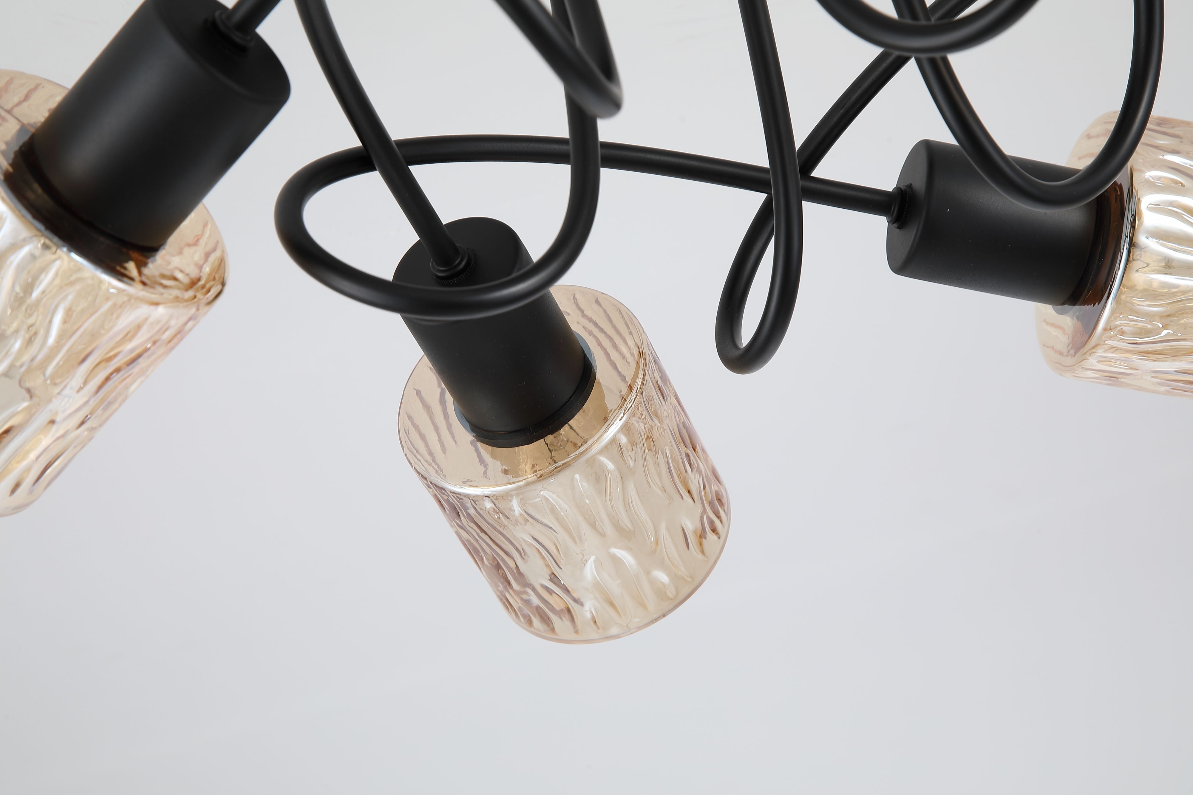 Close up of the Knot 5 Light ceiling lamp's rippled amber glass shades and knotted black metal arms