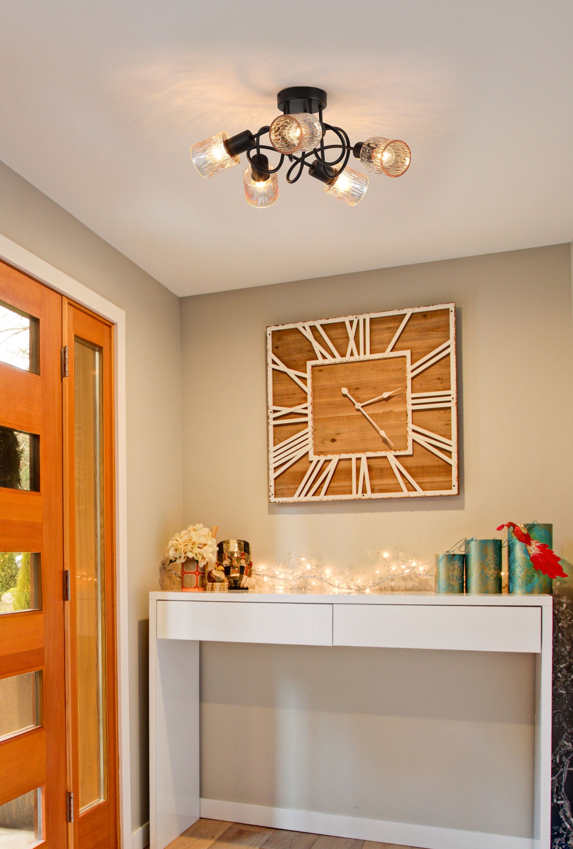 Searchlight Knot 5 Light Ceiling Lamp in matte black with amber glass shades styled on a hallway ceiling near a wall clock