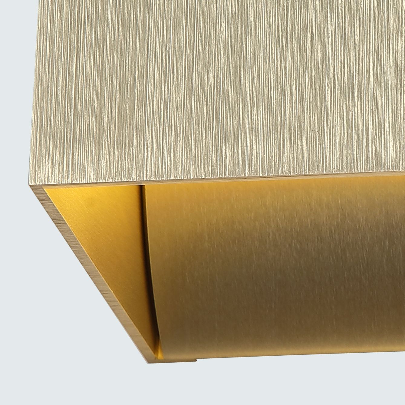 Close up of the underside of the Newton Square wall light in anodised gold, showing the brushed finish and the angled slot where light spills downward