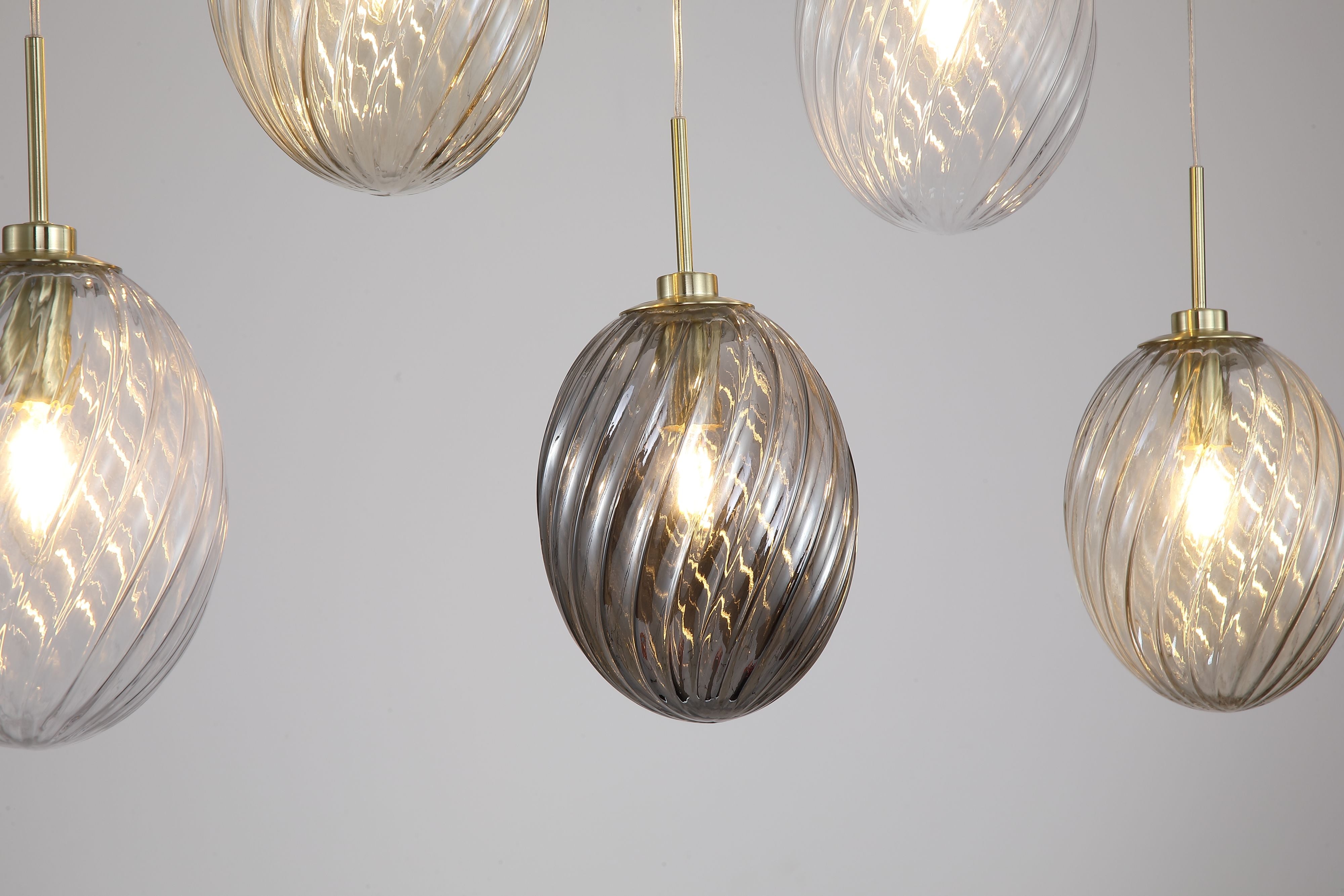Close up of the ribbed swirl texture on the clear, champagne and smoked glass shades of the Whirl 5 Light Bar Pendant, showing the satin brass fittings