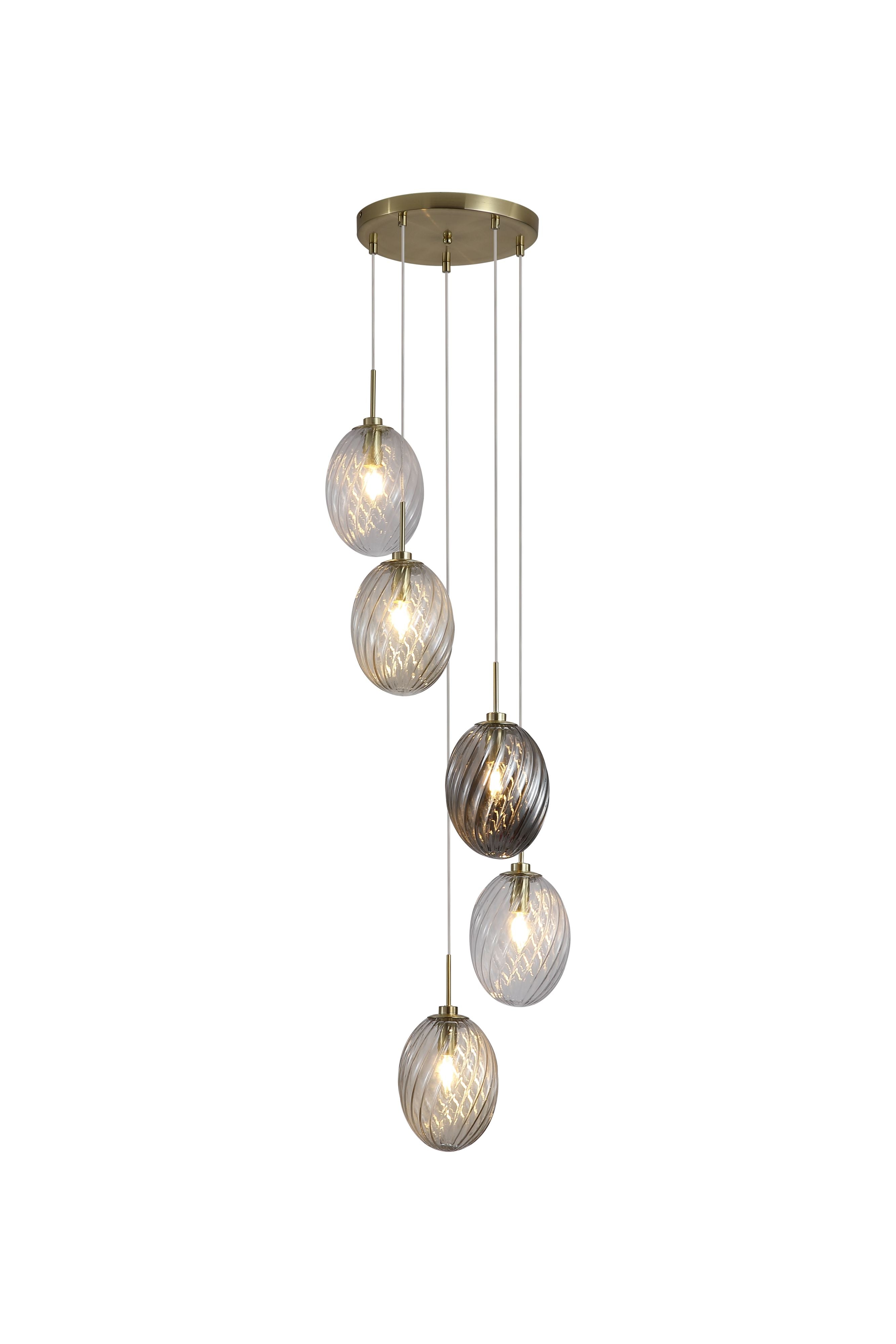 Searchlight Whirl 5 light multi drop pendant with a round satin brass ceiling plate suspending five staggered oval swirled glass shades in clear, champagne and smoked tones, against a plain white background