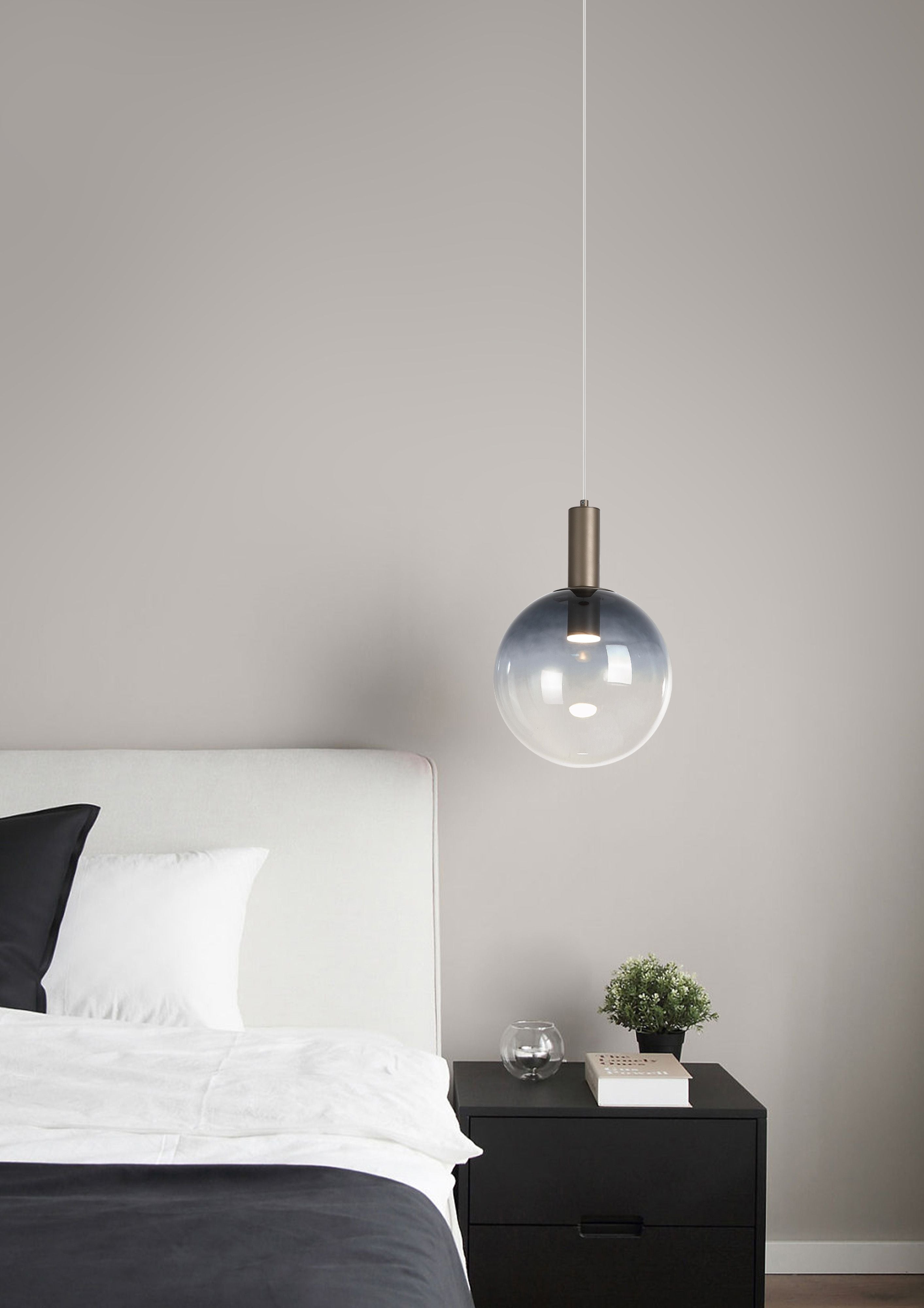 Smoked ombre glass Ombre pendant hanging beside a bed with a dark bedside table, small plant and book