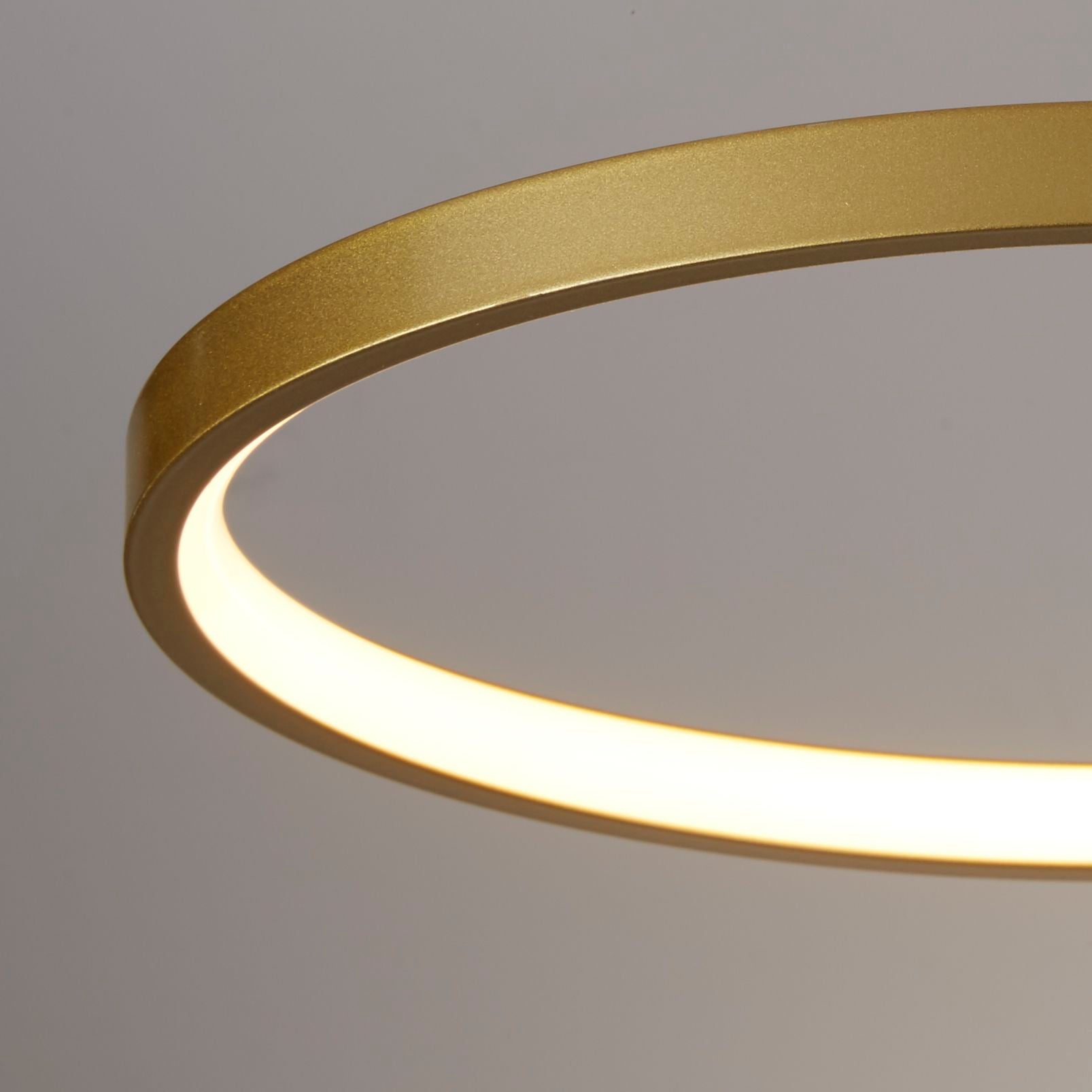 Close up detail of one gold ring on the Cirque flush light, showing the silicone diffuser edge glowing warm white