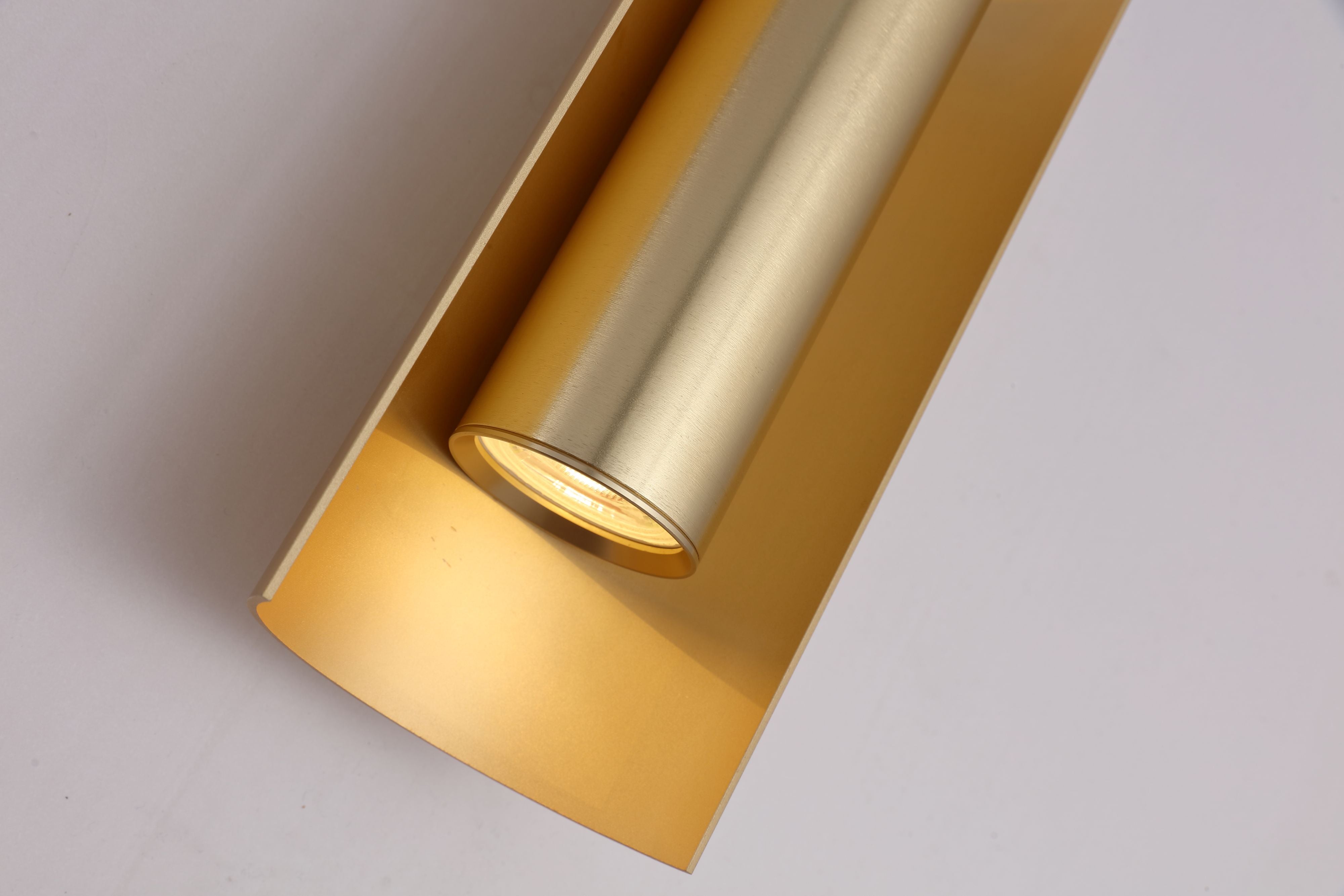 Close up of the Searchlight Roll 2 Light Wall Light in gold, angled view into the curved housing showing the GU10 bulb holder and brushed gold cylinder detail