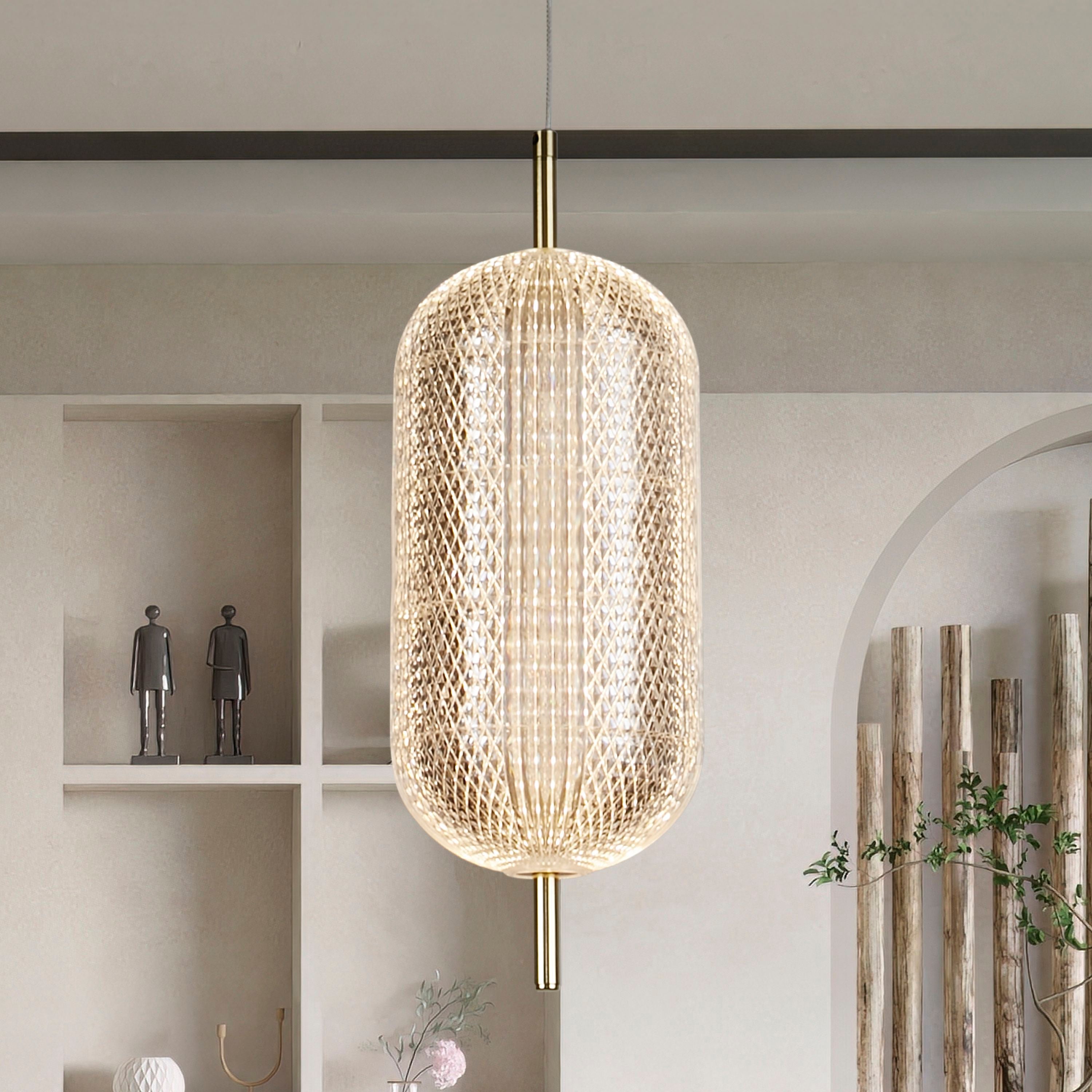 Searchlight Capsule LED pendant in satin brass styled above a shelving unit with sculptural ornaments and trailing plants, illuminated with a warm glow