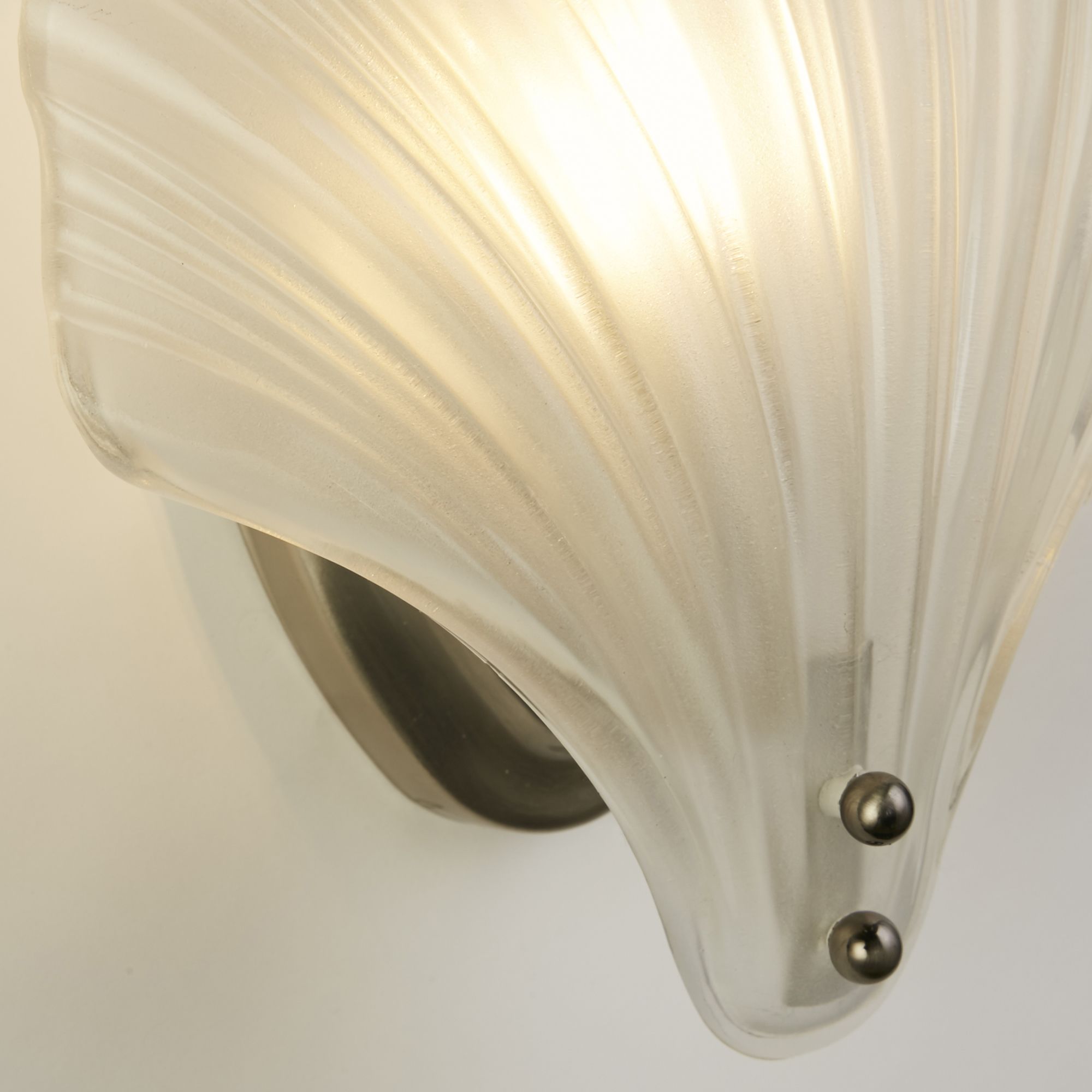 Close up of the Shell's frosted glass shade showing the ribbed texture and satin silver wall plate