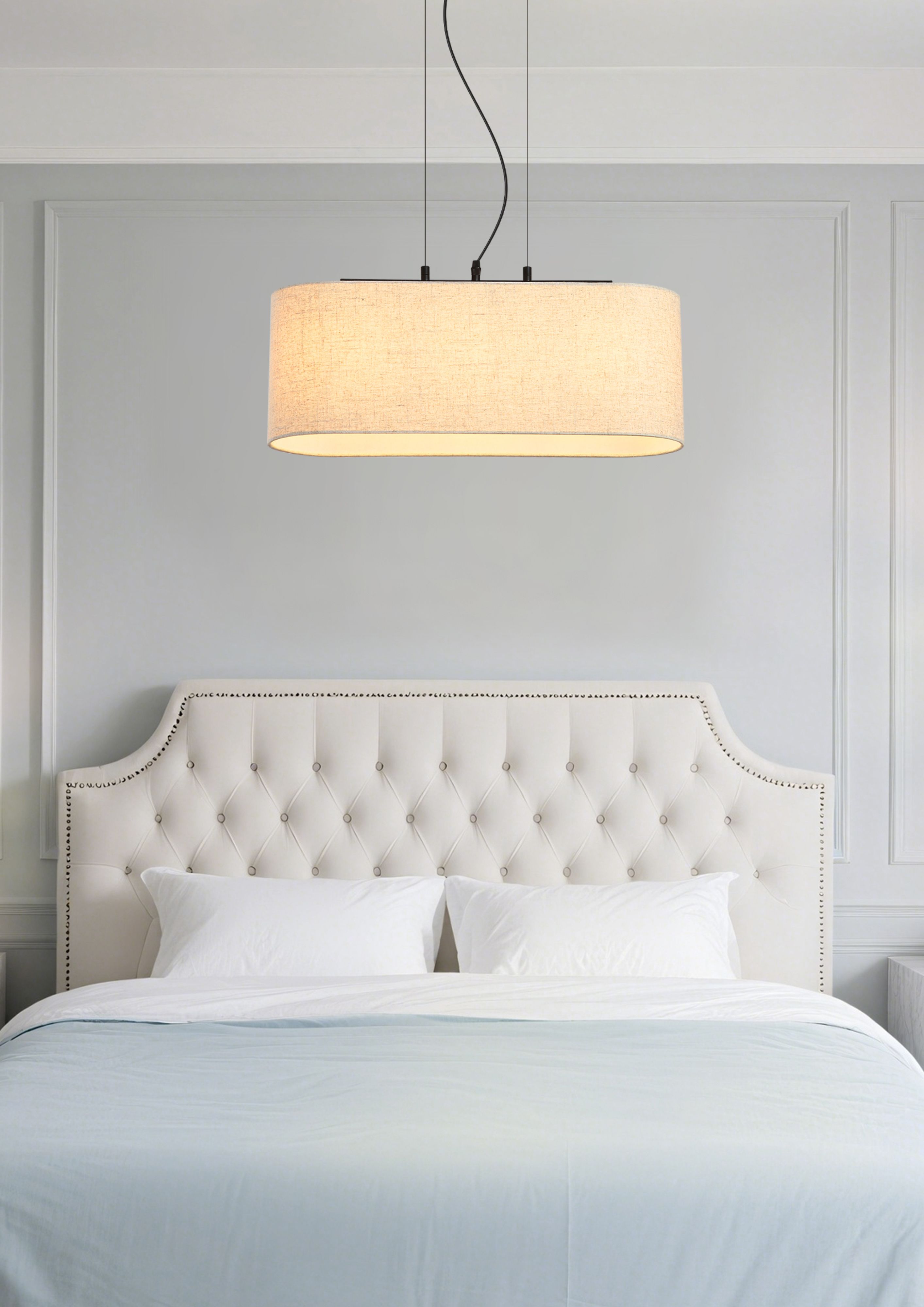 Searchlight Hessian 3 light pendant switched on above a bed, hung low over a tufted headboard in a styled bedroom