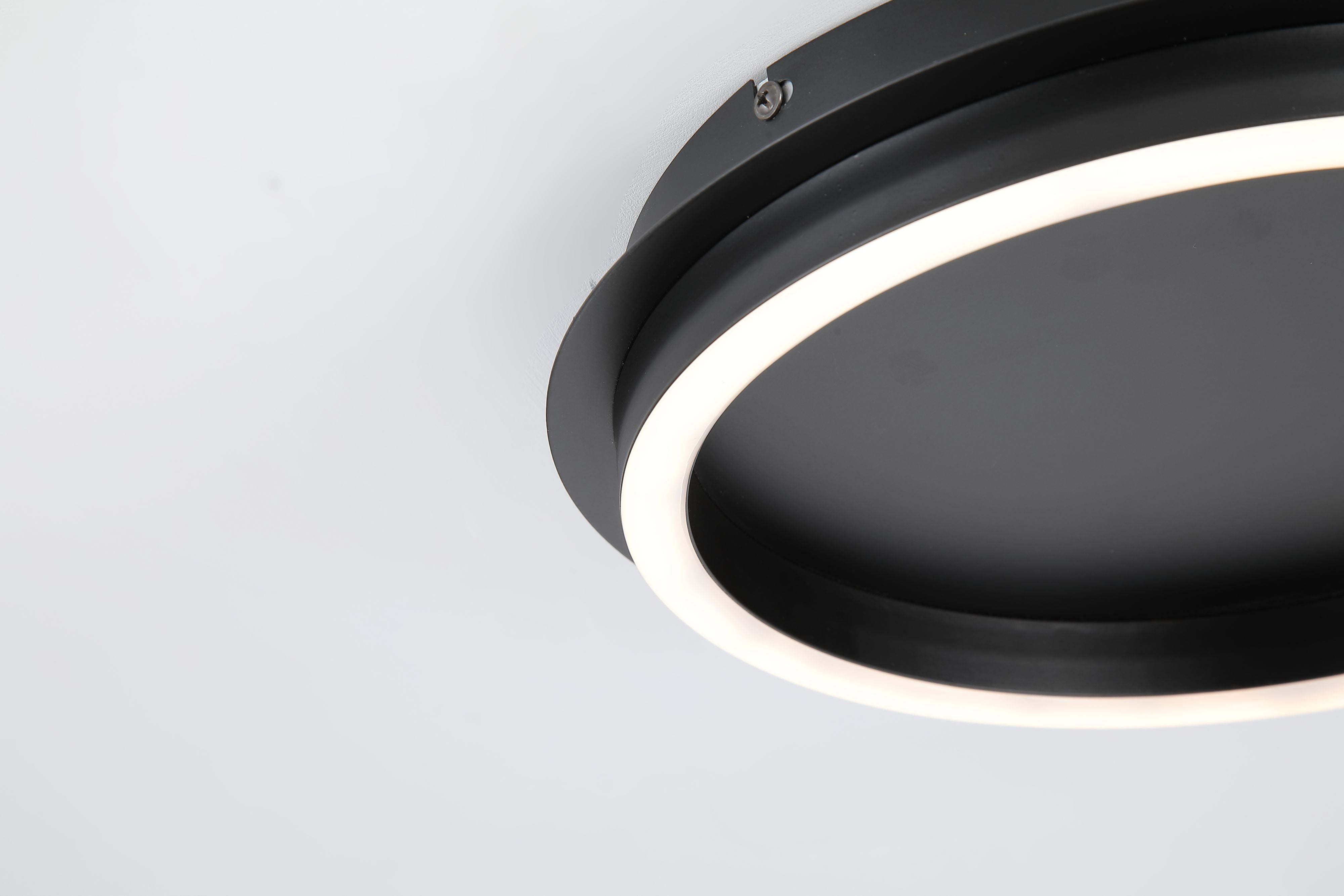 Close up of the Searchlight Stellar LED ceiling lamp showing the fixing screw and lit acrylic diffuser ring against the black frame