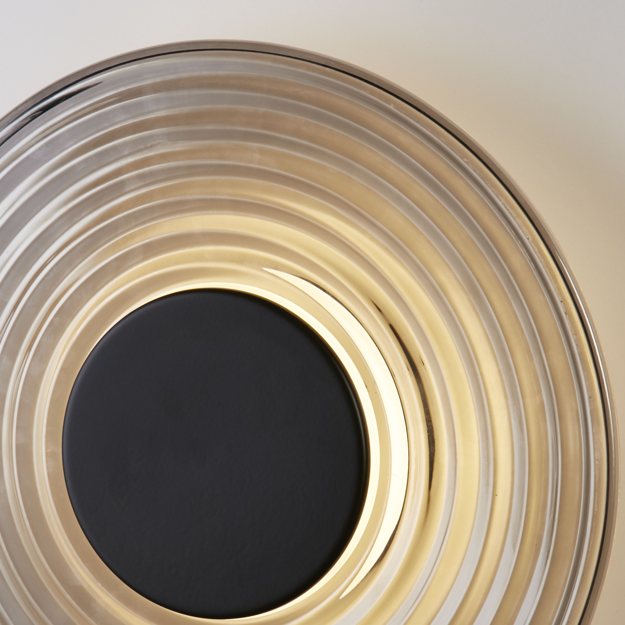 Close up of the Cleo wall light's ridged smoked glass and matt black centre disc, showing the textured rings in detail
