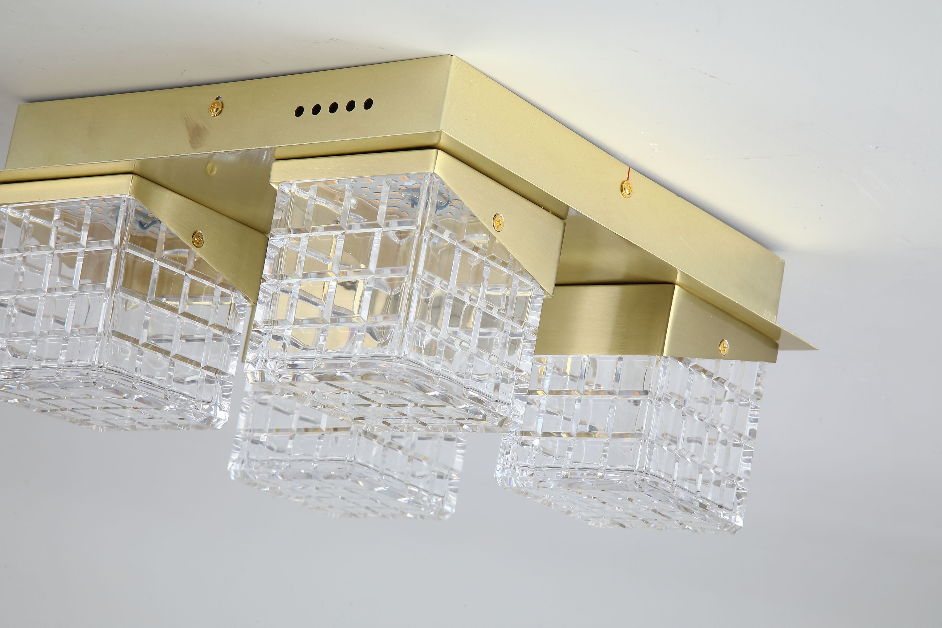 Close up of the satin brass frame and faceted acrylic cube texture on the Cuboid 4 Light Flush, lit