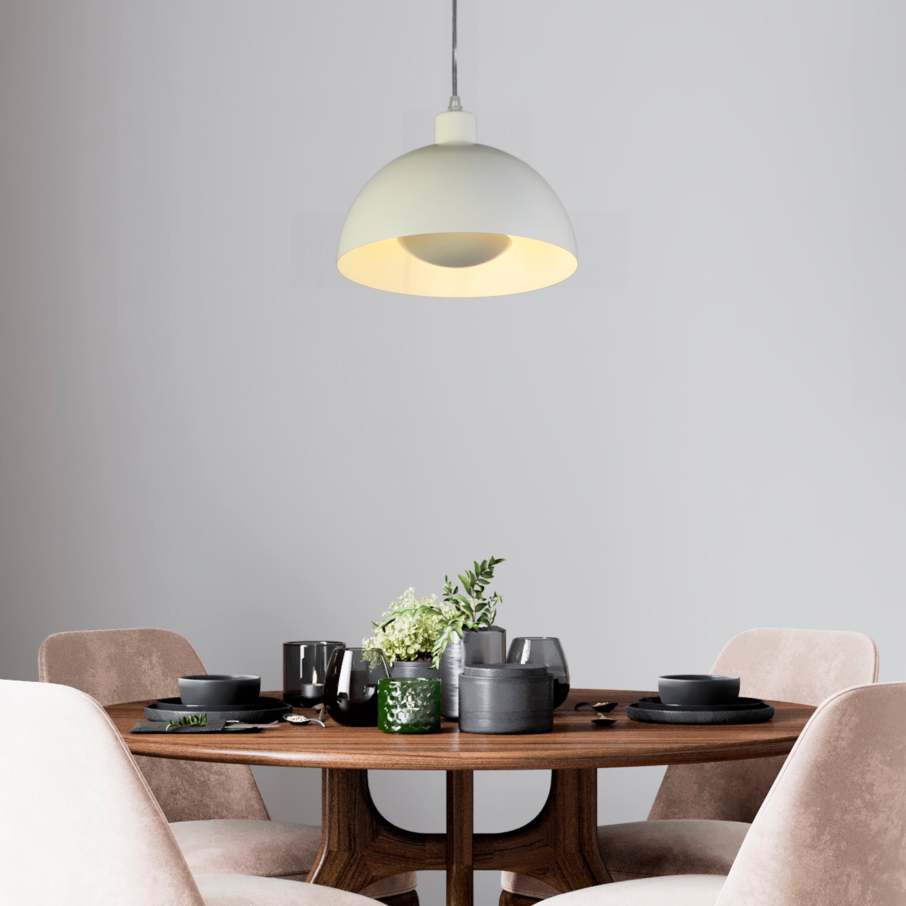 Searchlight Mars pendant in matt cream metal hung above a dark wood dining table set with black tableware and greenery